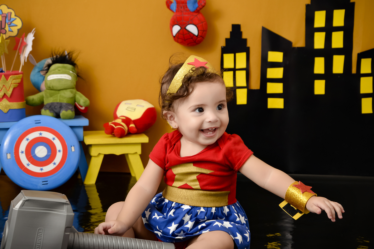 Drica Studio Fotografias - Drica Studio - Xinguara Pará - Acompanhamento Mensal - fotos com roupa mulher maravilha - cenário super herói - coroa dourada - martelo - escudo 