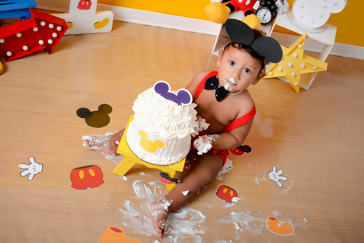 Drica Studio - Drica Studio Fotografias - Drica Studio Xinguara Pará - Ensaio de 1 ano - Smash the cake - Cenário Mickey mouse - urso - balões vermelho - amarelo - preto - fundo amarelo - roupa do Mickey - comendo bolo - lambuzado 