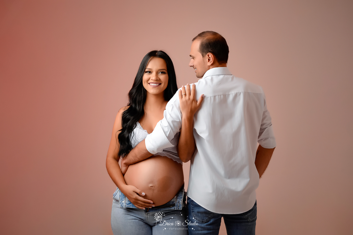 Drica Studio - Drica Studio Fotografias - Drica Studio Xinguara Pará - fotos de gestante - gravidinha - casal - calça jeans - camisa branca - sutiã branco - fotos clean - fundo claro - marido olhando 