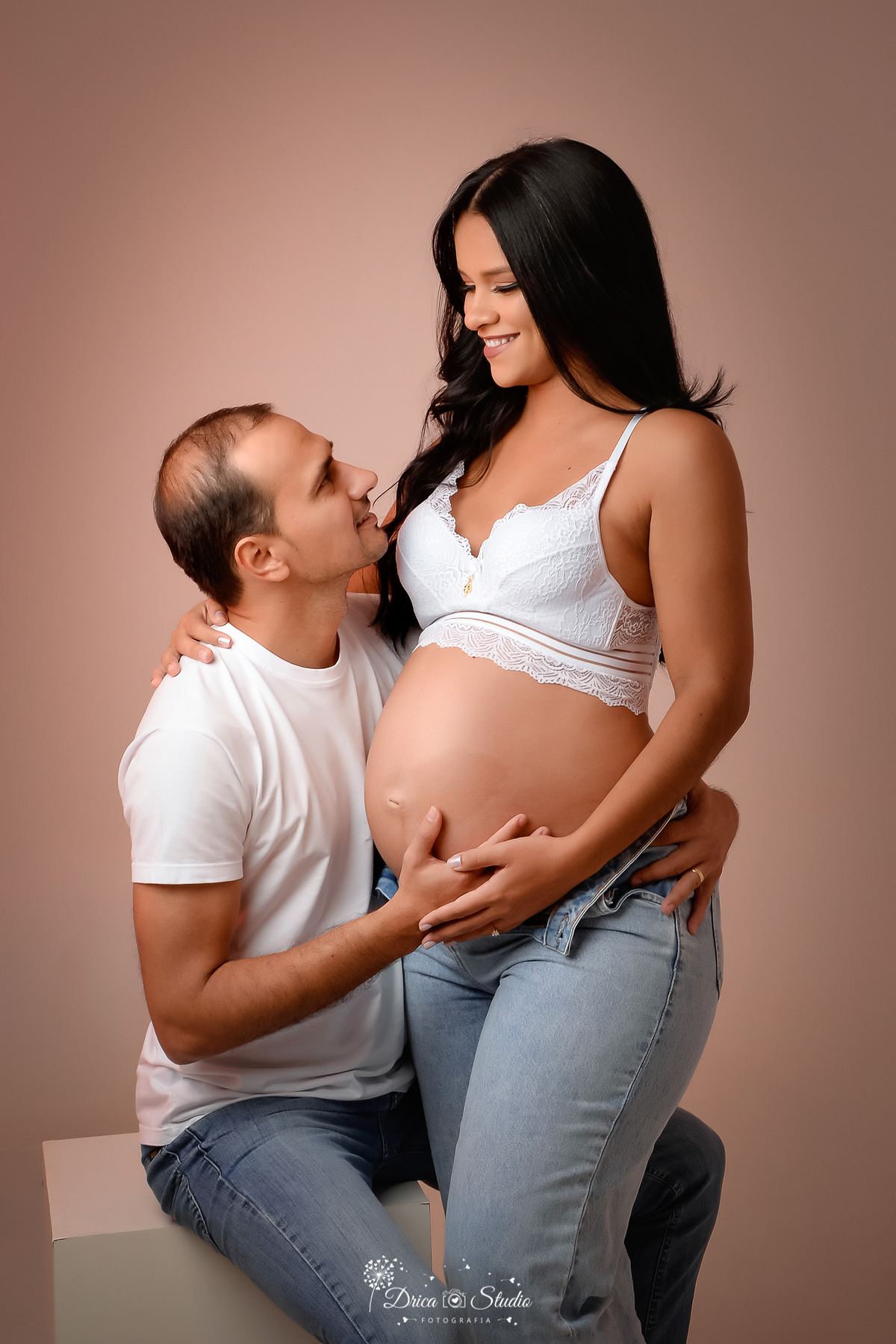 Drica Studio - Drica Studio Fotografias - Drica Studio Xinguara Pará - ensaio de gravida - marido e mulher - roupas composta em tons mais claros - branco - calça jeans - mão na barriga - olhando um para o outro - abraçados 