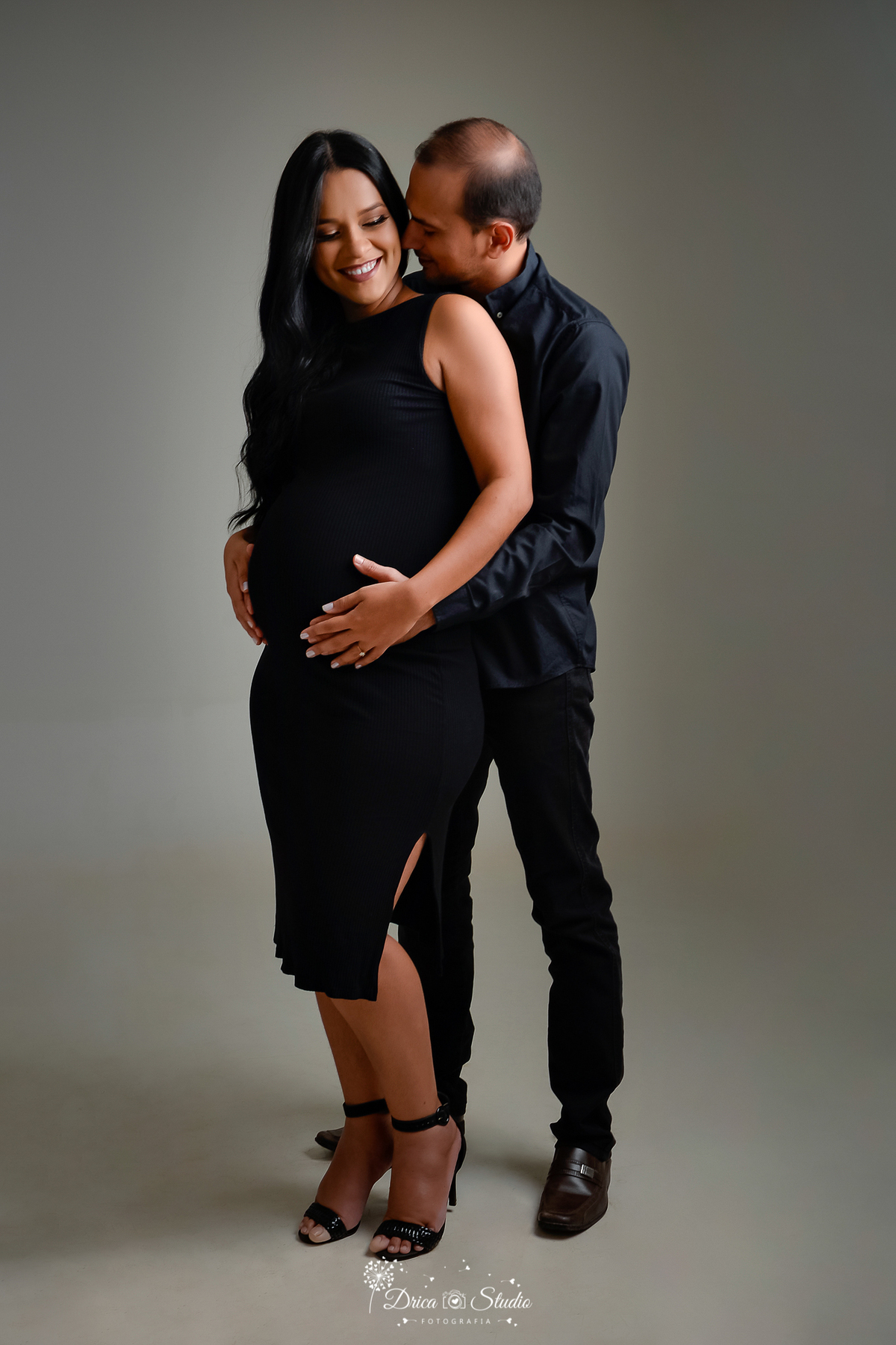 Drica Studio - Drica Studio Fotografias - Drica Studio Xinguara Pará - Ensaio de gestante - Marido e Mulher - fotos de gravida - mão no pescoço - roupa preta - casal - mãos na barriga - se olhando - gravidinha - gestação - cheiro no cangote - fundo cinza 