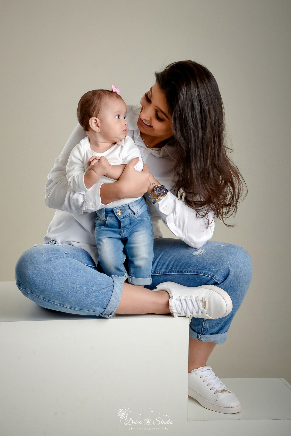 Drica Studio - Drica Studio Fotografias - Xinguara Pará - ensaio mãe e filha - Studio - Clean - roupas tons claros - brancas - calças jeans - fundo cinza - olhando uma pra outra - brincando - sapato branco - mãe de menina