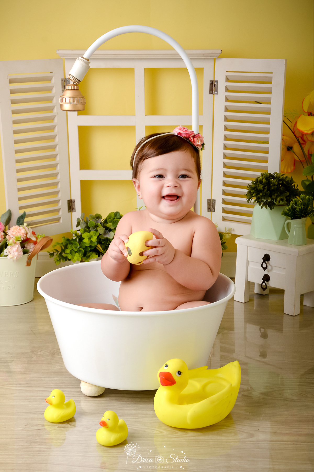 drica studio - ensaio fotográfico - xinguara - menina com tiara de flhores na cabeça, banhando em banheira branca - cômoda branca com vasos verdes erva doce - janela branca