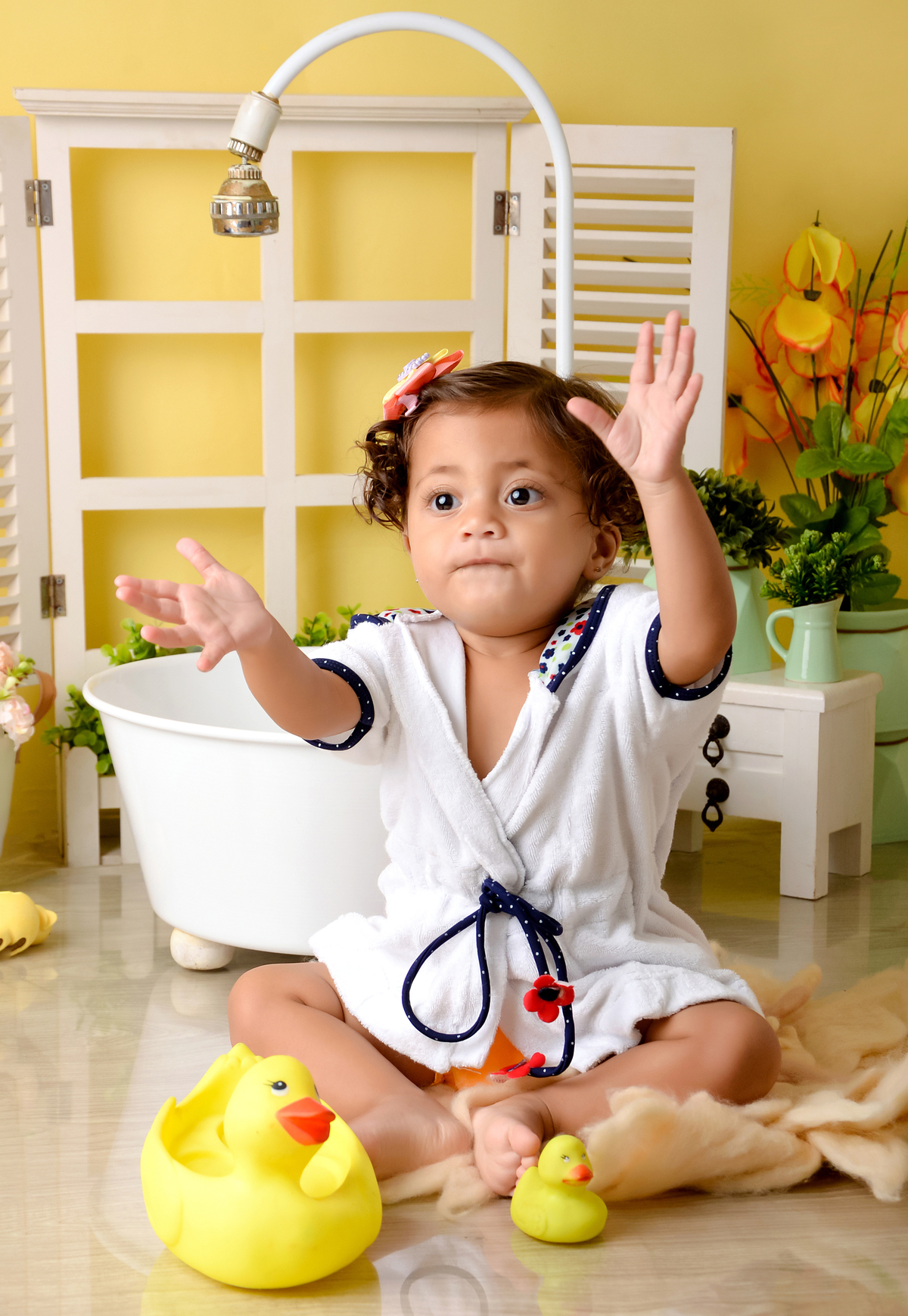 drica studio - ensaio fotográfico - xinguara - menina de cabelos cacheados vestindo roupão branco com detalhes azuis, batendo palmas - banheira branca - cômoda branca - fundo amarelo