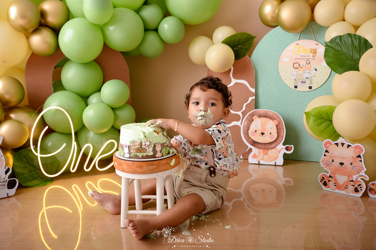drica studio - ensaio fotográfico - xinguara - smahs the cake safari - bichinho safari baby - painel verde - painel de girafa - menino comento bolo - cadeirinha branca