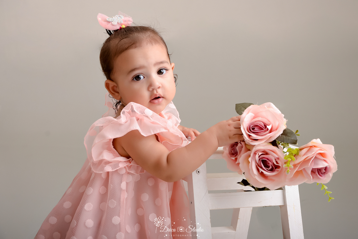 drica studio - ensaio fotográfico infantil - xinguara - bebê vestindo vestido rosa de tule - flores rosa - banquinho branco - funco branco