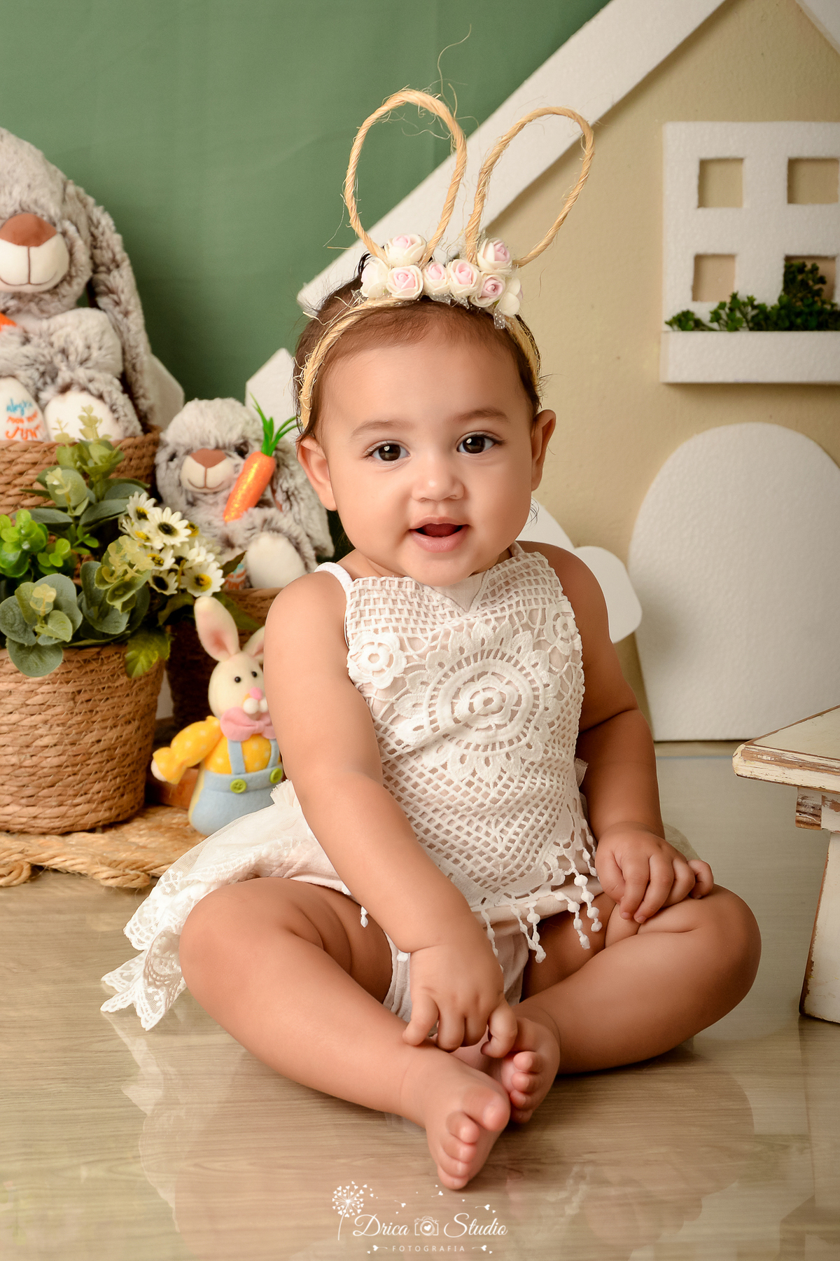 drica studio - ensaio fotográfico infantil - xinguara - cenário de páscoa - bebê sorridente - coelhos de pelúcia - cesto de palha com flores brancas - bory de renda creme - fundo verde