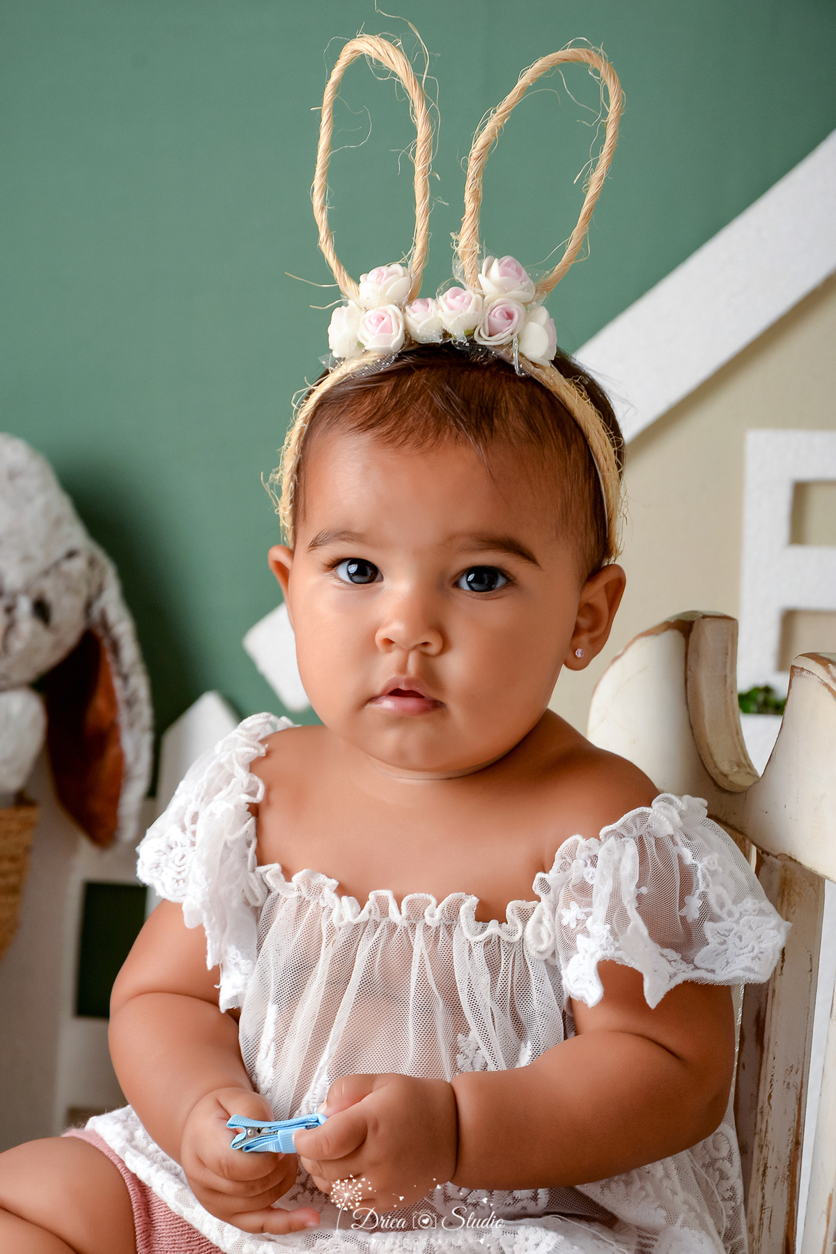 drica studio - ensaio fotográfico infantil - xinguara - páscoa - bebê vestindo blusa branca de rendo - tiara com orelhas de coelho - coelho - cadeira branca 
