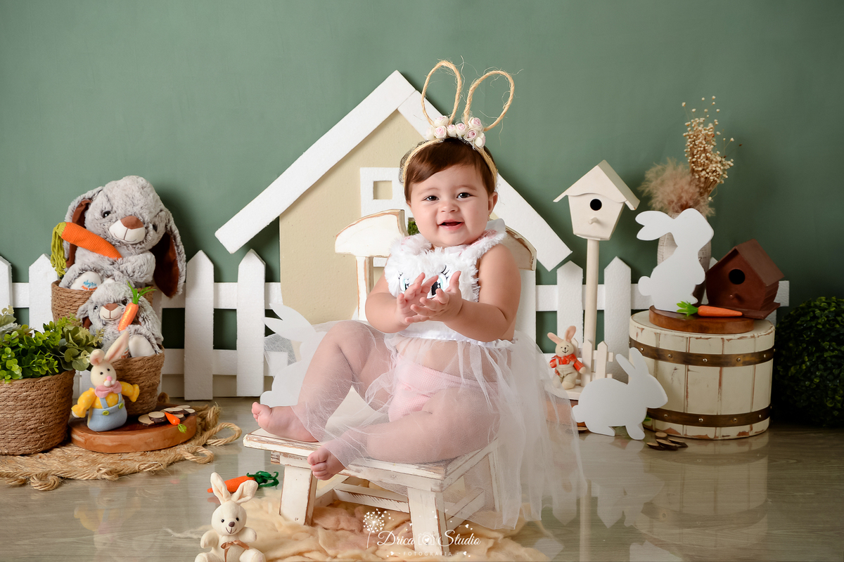 drica studio - ensaio fotográfico infantil - xinguara - páscoa - coelhos - menina vestindo roupinha de tule com tiara com orelha de coelho - cadeira branca - cenoura - casa de coelho