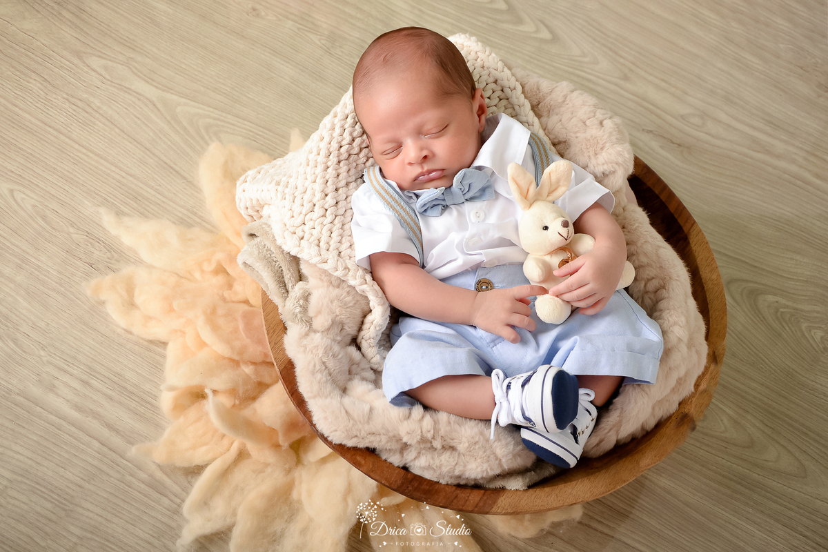 drica studio - ensaio fotográfico infantil - xinguara - páscoa - bebê dormindo dentro de gamela - coelho - tapete felpudo - piso amadeirado - roupinha social azul e branco
