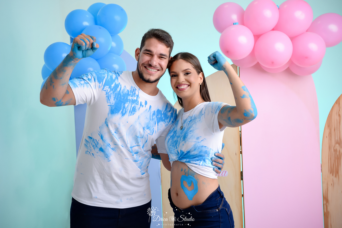 drica studio - ensaio fotográfico - chá revelação - xinguara - casal de camiseta branca sujos de tinta azul comemorando - balões azul e rosa - painel rosa - fundo azul