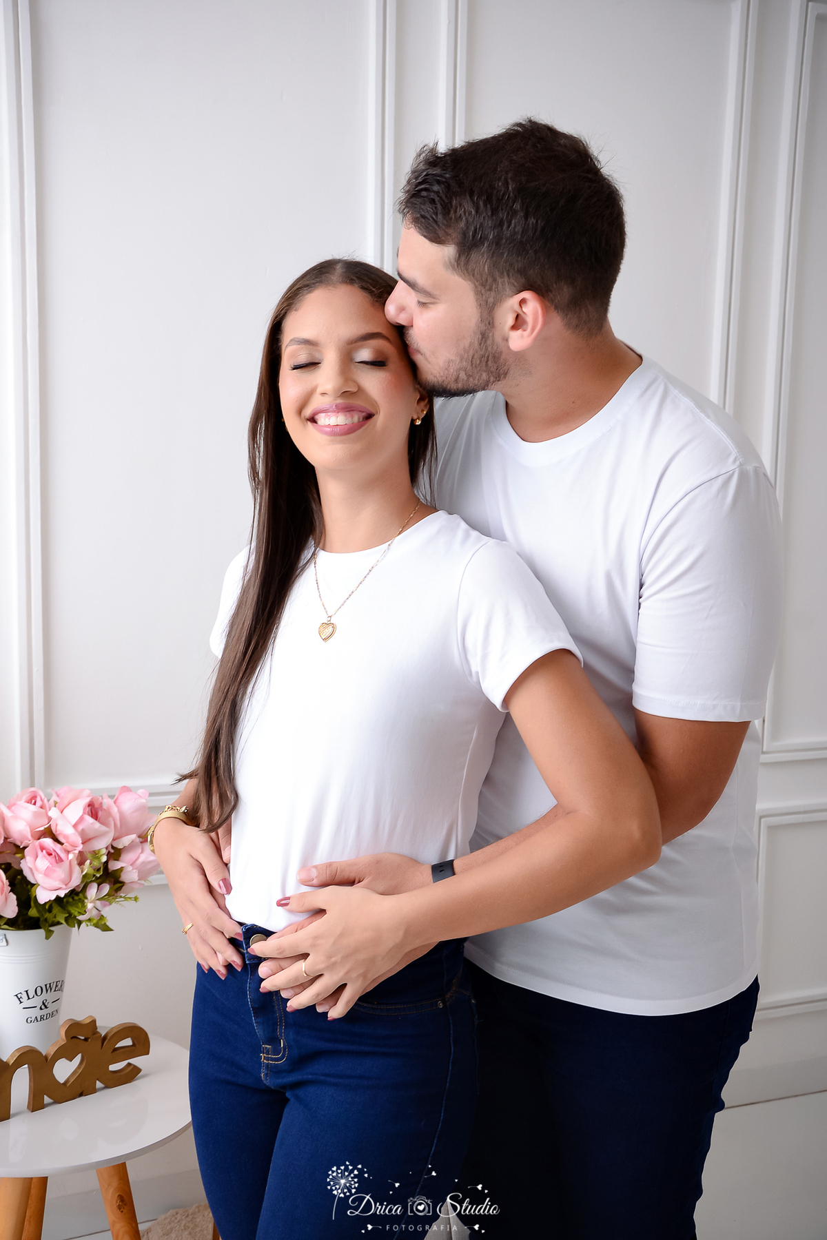 drica studio - ensaio fotográfico - chá revelação - xinguara - casal usando camisetas branca - flores rosa - esposo abraçando esposa