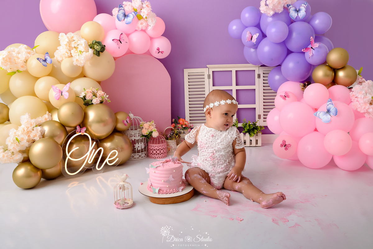 Drica studio - ensaio fotográfico - xinguara - jardim encantado - smash the cake - janela branca - one - flores - bolo rosa - bebê esmagando bolo - borboletas - gaiolas - balão dourado, rosa, lilás e creme