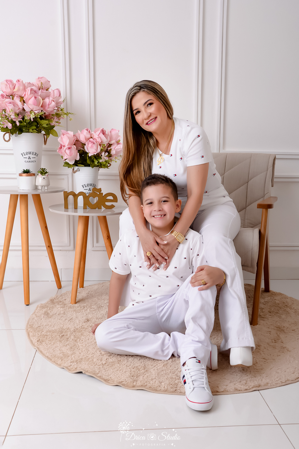 drica studio, ensaio fotografico, xinguara, dia das mães, filho sentado no chão entre pernas da mãe, camisetas branca com poá vermelho, calça branca, mesinha de canto, poltrona de madeira e estofado cinza, carpete redondo