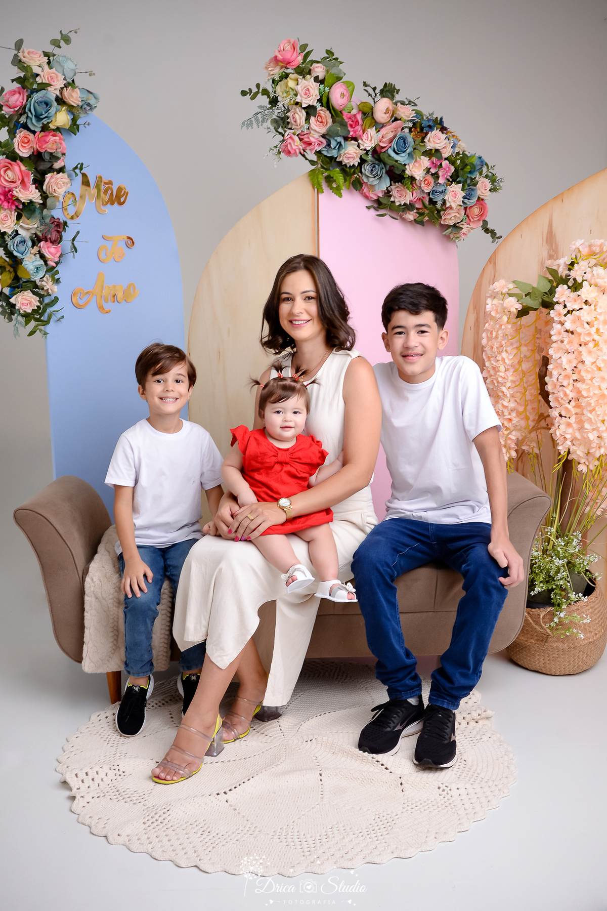 drica studio, ensaio fotografico, xinguara, dia das mães, fundo azul e rosa, devam marrom, camisetas brancas, vestindo vermelho, vestido branco, arranjo floral, mães com os 3 filhos.