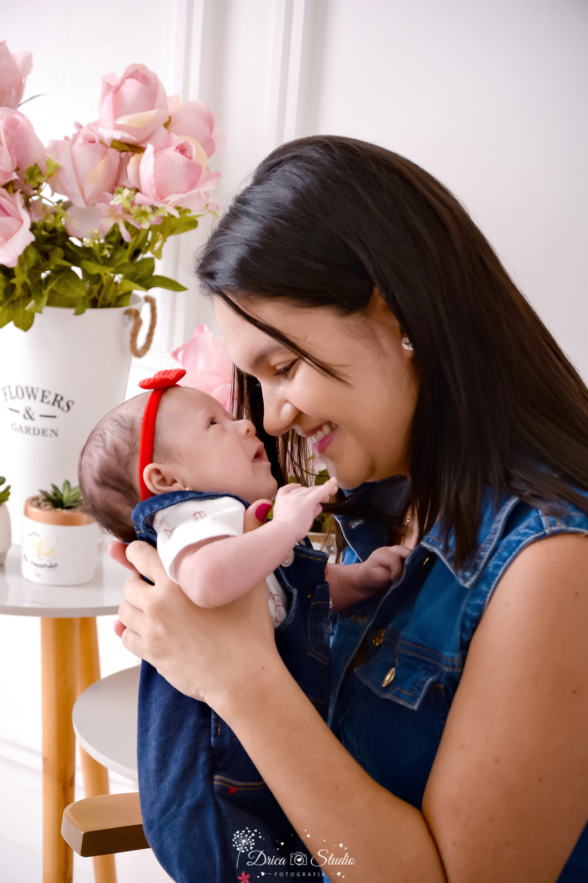 drica studio, ensaio fotografico, xinguara, dia das mães, mãe segurando bebê próximo ao rosto, vestido jeans, macaquinho jeans e blusa branca, laço vermelho, vaso branco