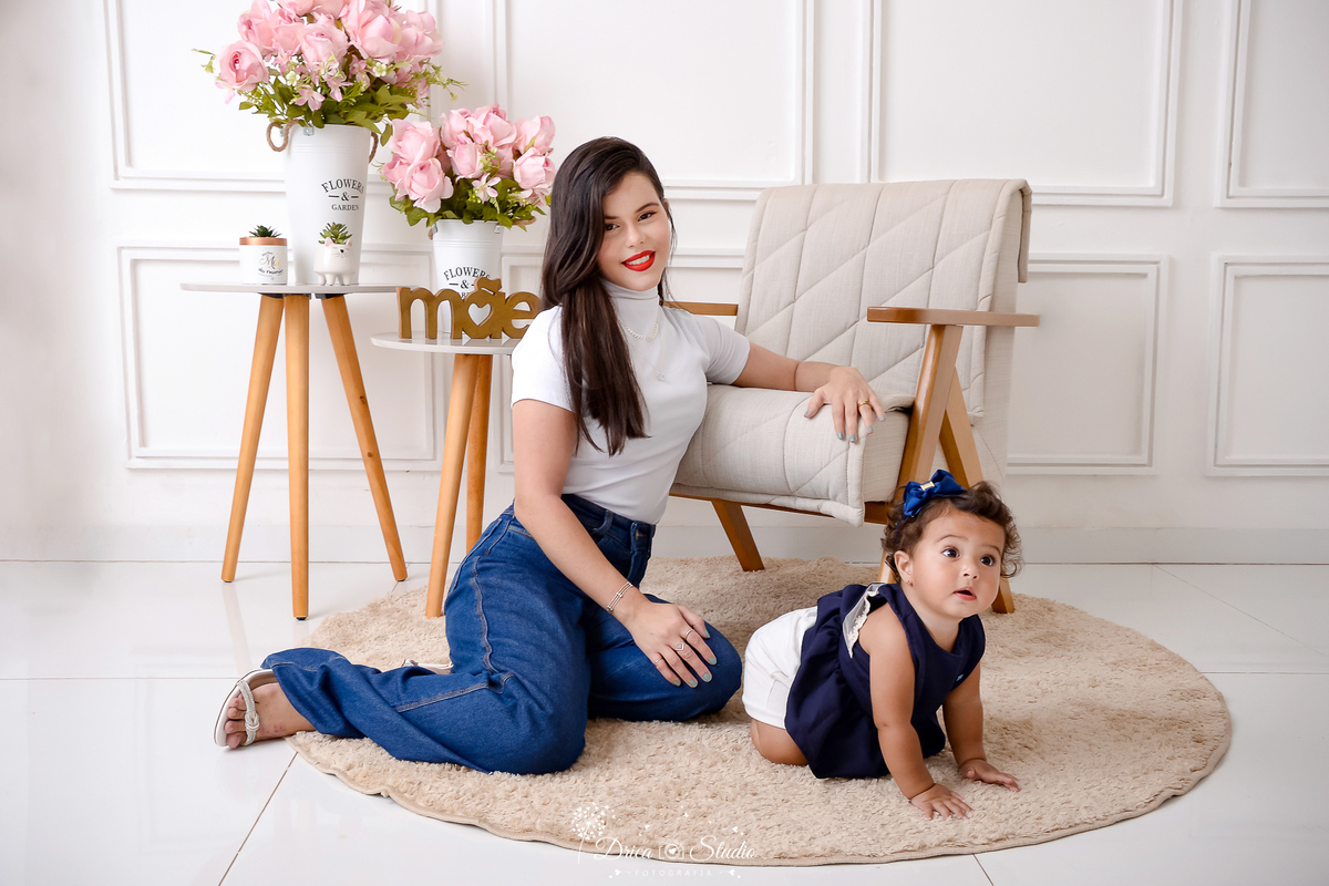 drica studio, ensaio fotografico, xinguara, dia das mães, mãe sentada no chão, menina engatinhando, carpete redondo bege, mesinha de canto, fundo branco com boiserie, flores rosa