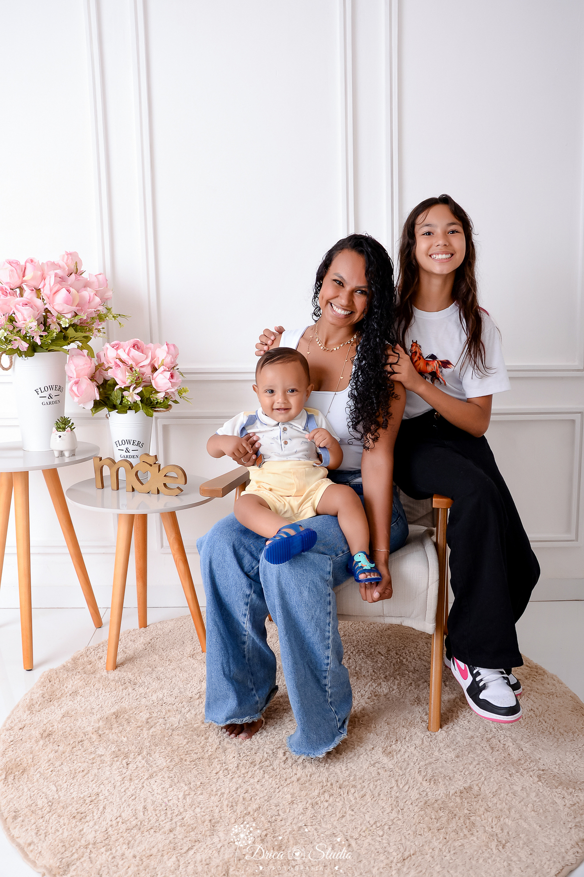 drica studio, ensaio fotografico, xinguara, dia das mães, mãe com casal de filhos, bebê vestindo short amarelo e camisa azul clara, menina vestindo calça preta e blusa branca, mãe vestindo blusa branca e calça jeans, fundo branco com boiserie