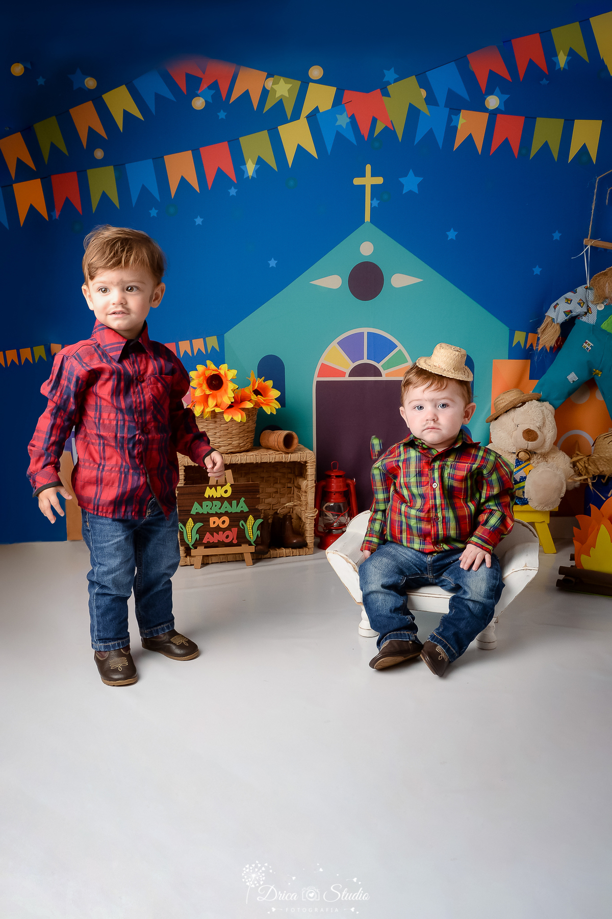 Drica studio - ensaio fotográfico infantil- xinguara - festa junina - camisa xadrez - calça jeans - fundo com tema junino - cesto de palha com girassois - espantalho - ursinho branco - fogueira de eva - lampião vermelho