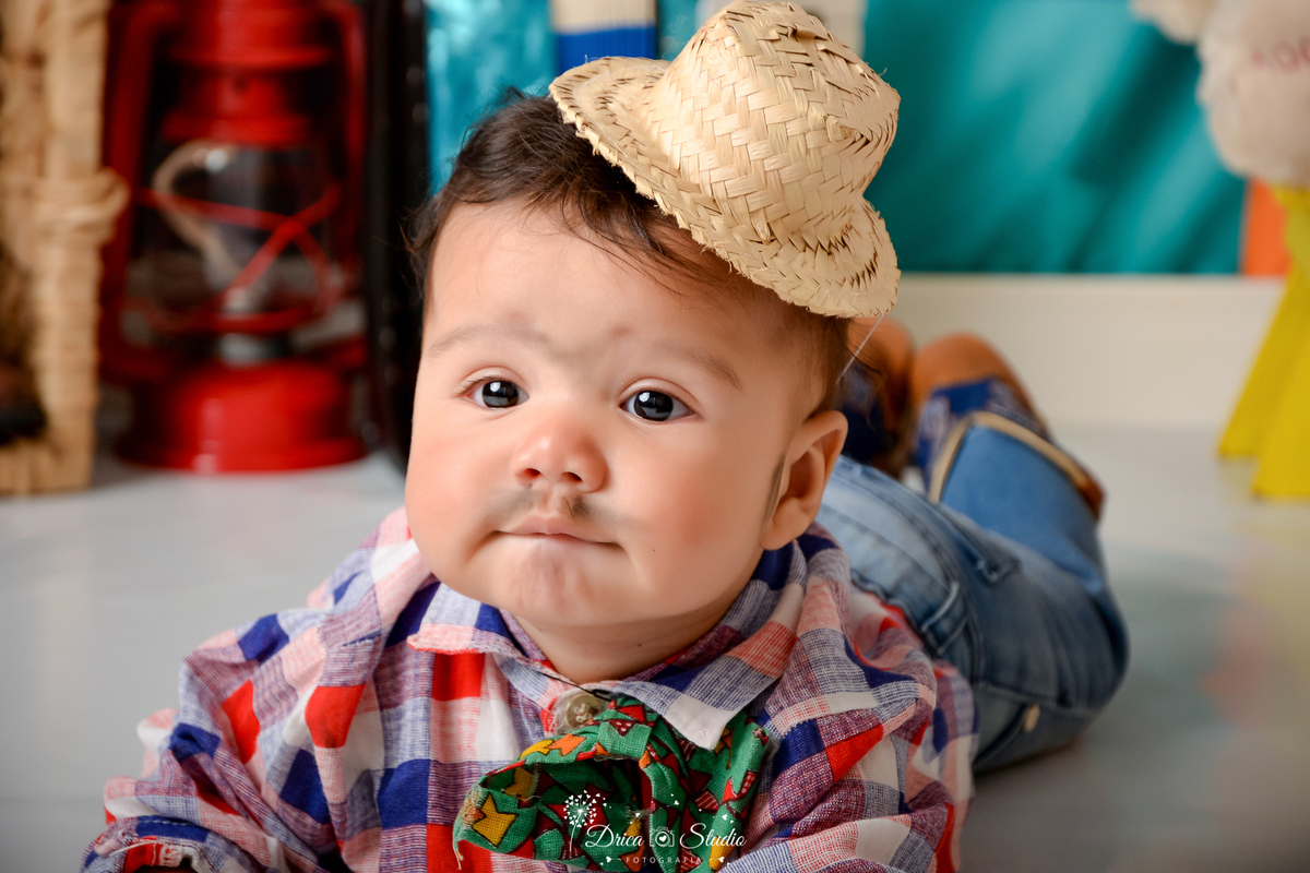 Drica studio - ensaio fotográfico infantil- xinguara - festa junina - bebê vestindo roupa caipira deitado de bruços no chão - lampião vermelho - banquinho amarelo - fundo colorido