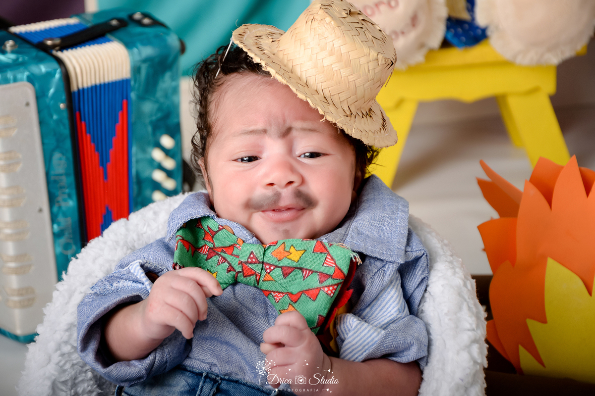 Drica studio - ensaio fotográfico infantil- xinguara - festa junina - bebê vestindo em camisa azul - chapéu de palha - fogueira - banquinho amarelo - sanfona azul - poltrona branca