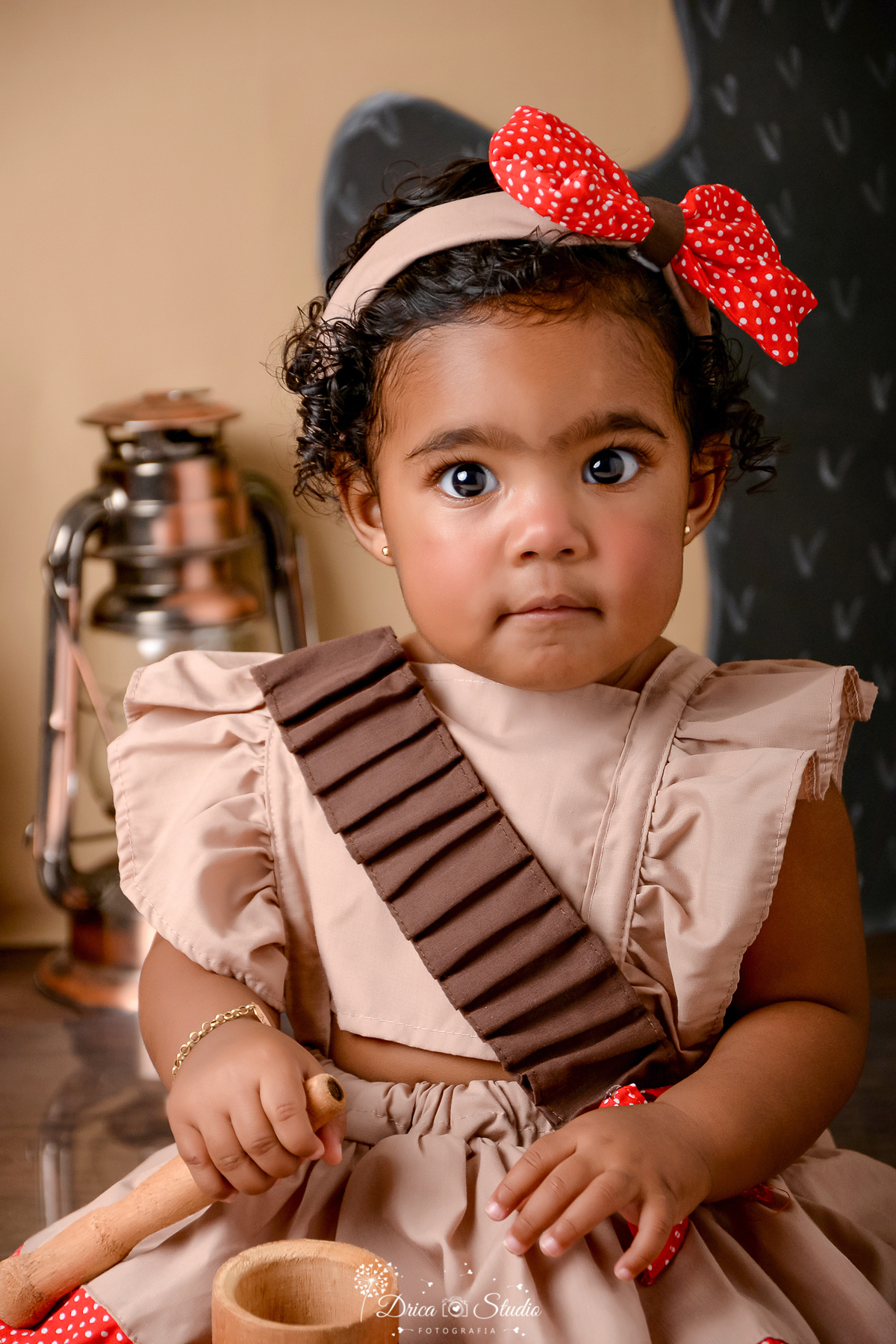 drica studio - ensaio fotografico infantil - tema sertão nordestino -  - menina morena vestindo roupa begem com detalhe marrom - lampeão - fundo de cordel