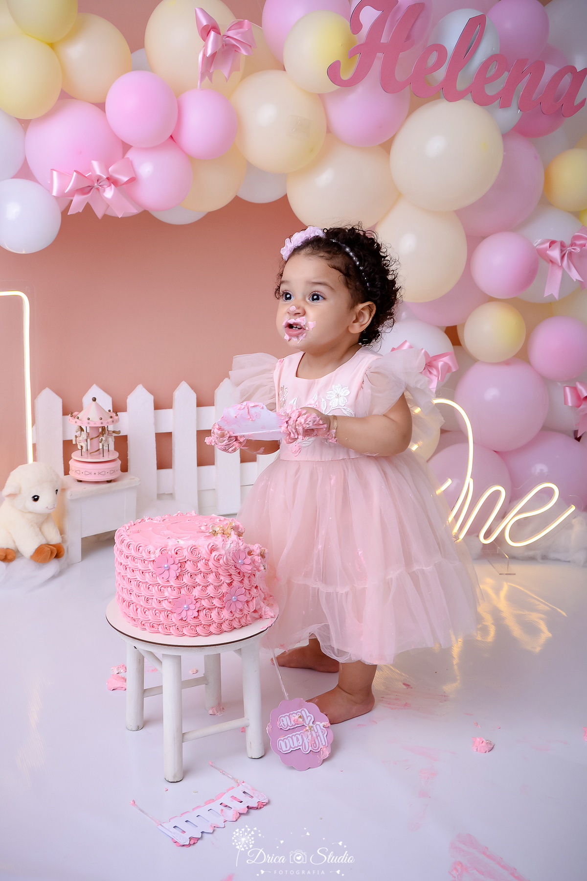 drica studio - ensaio fotográfico infantil - smahs the cake - ovelhinha - xinguara - vestido princesa infantil rosa -  bebê em pé perto do bolo rosa - cerca branca - carrossel rosa - one led - fundo rose