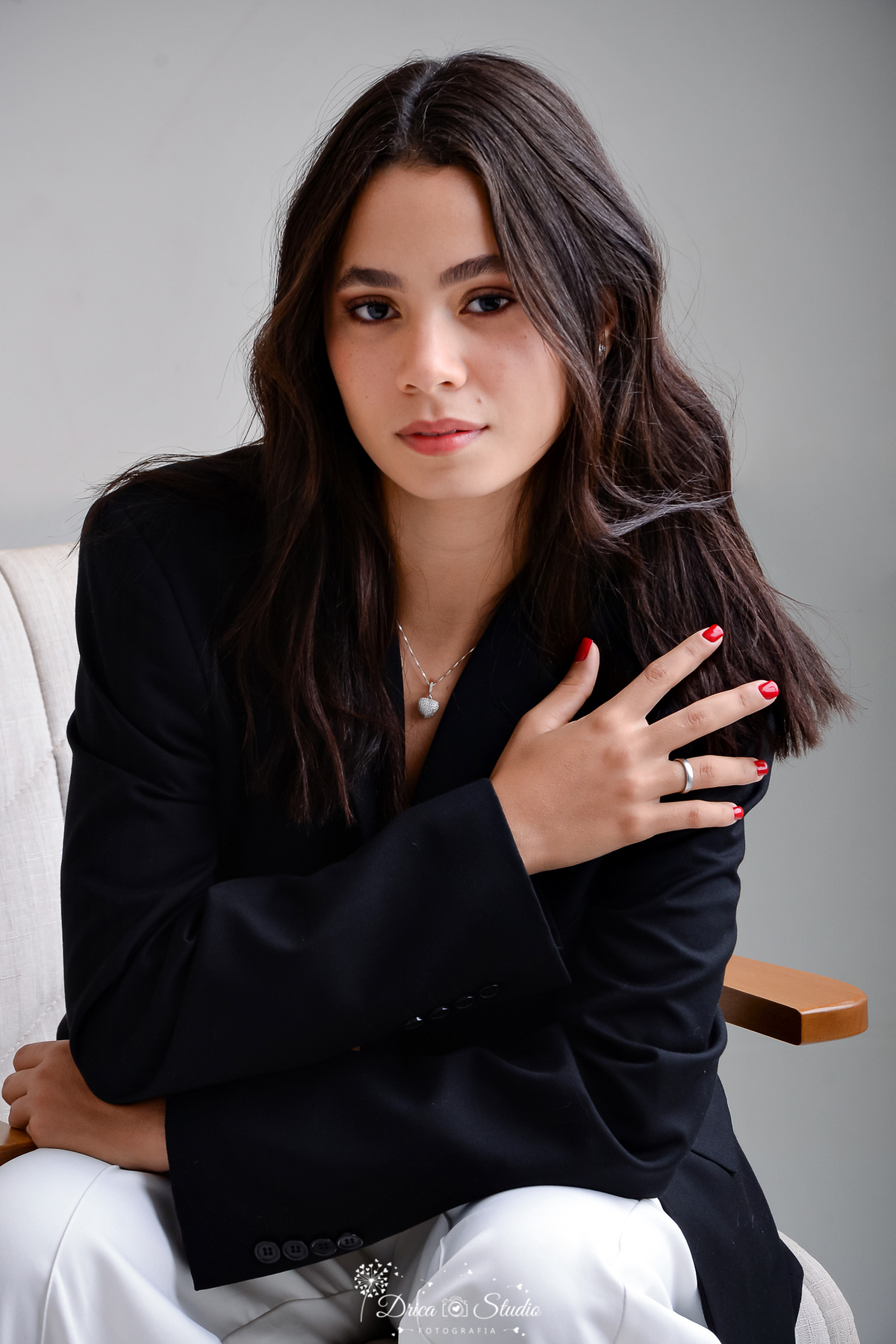 drica studio - ensaio fotográfico - aniversárlo 19 anos - xinguara - mulher sentada em poltrona clara, vestindo blazer preto, com cabelos solto 
