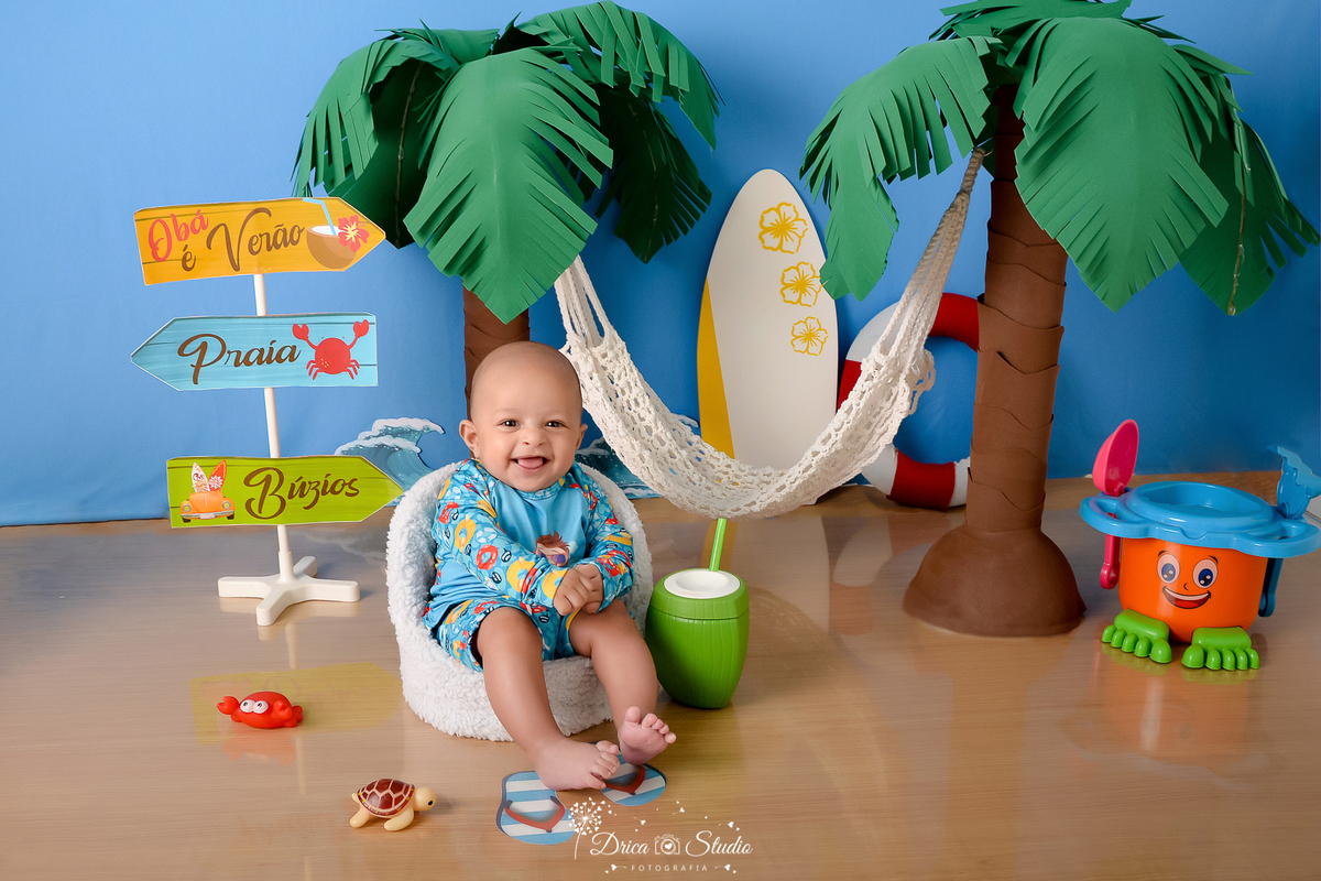drica studio - ensaio fotográfico infantil - verão e praia - bebê drica studio - ensaio fotográfico infantil - verão e praia - coqueiros - prancha de sulf branca com flores amarelas - baldinho de brinquedo laranja com azul e verde - coco verde com canudo 