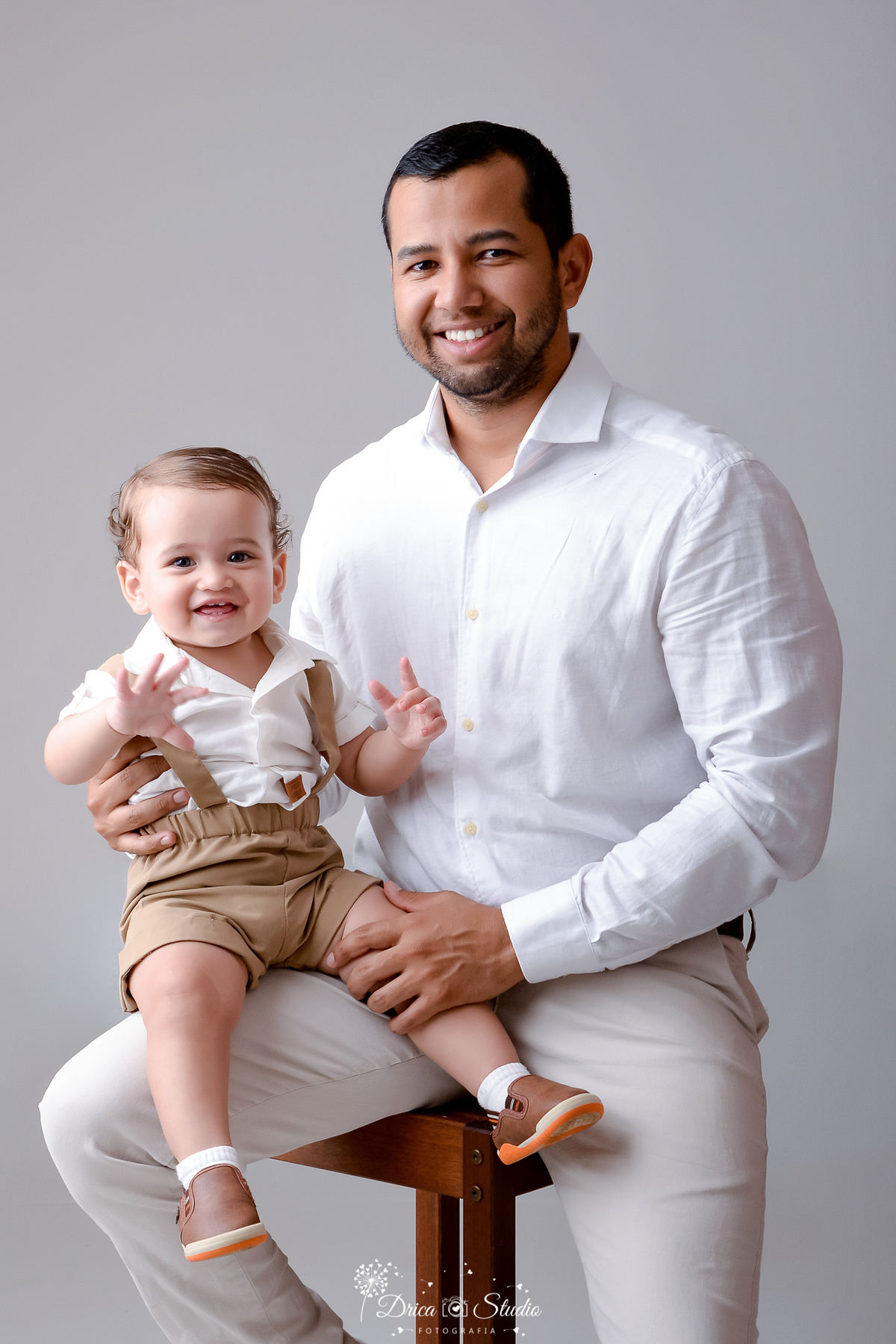 drica studio - ensaio fotografico dia dos pais - xinguara - homem vestindo camisa branca,  segurando bebê no colo - bebê usando camisa branca, short marrom com suspensório