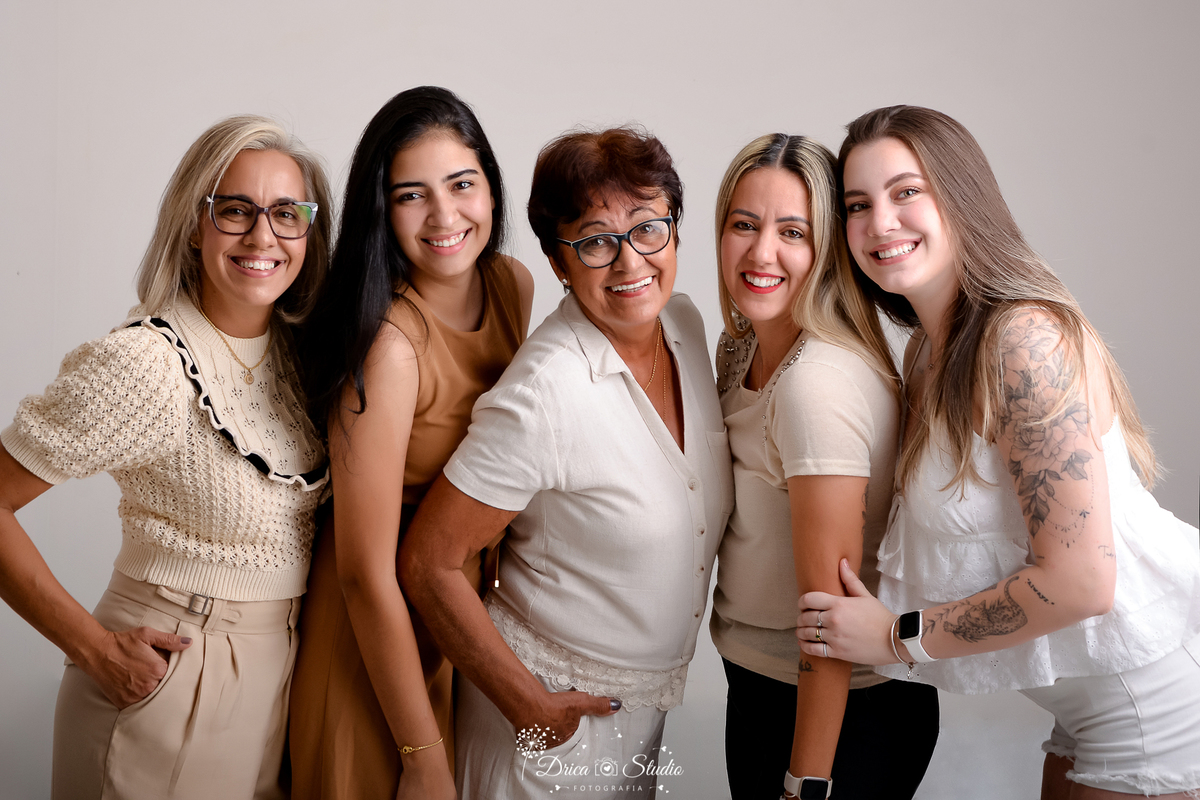 drica studio - ensaio fotografico - família - xinguara - cinco mulheres encostada uma na outra - três loira e duas morenas - blusa bege - vestido marrom - calça preta - short branco - fundo neutro