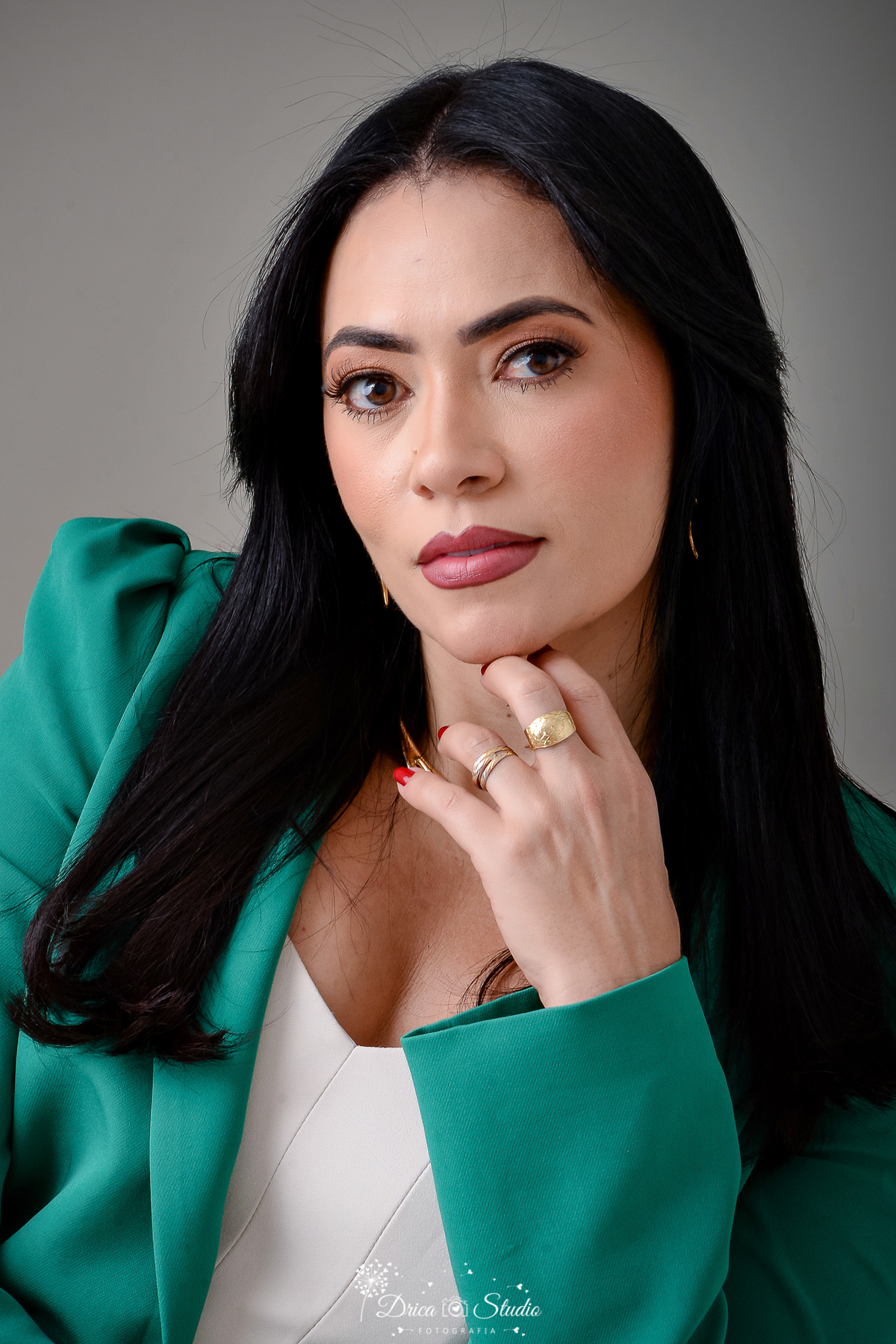 drica studio - ensaio fotografico - aniversário - profissional - xinguara - mulher ventindo croped na cor creme e blazer verde esmeralda, usa aneis nos dedos do meio - fundo neutro