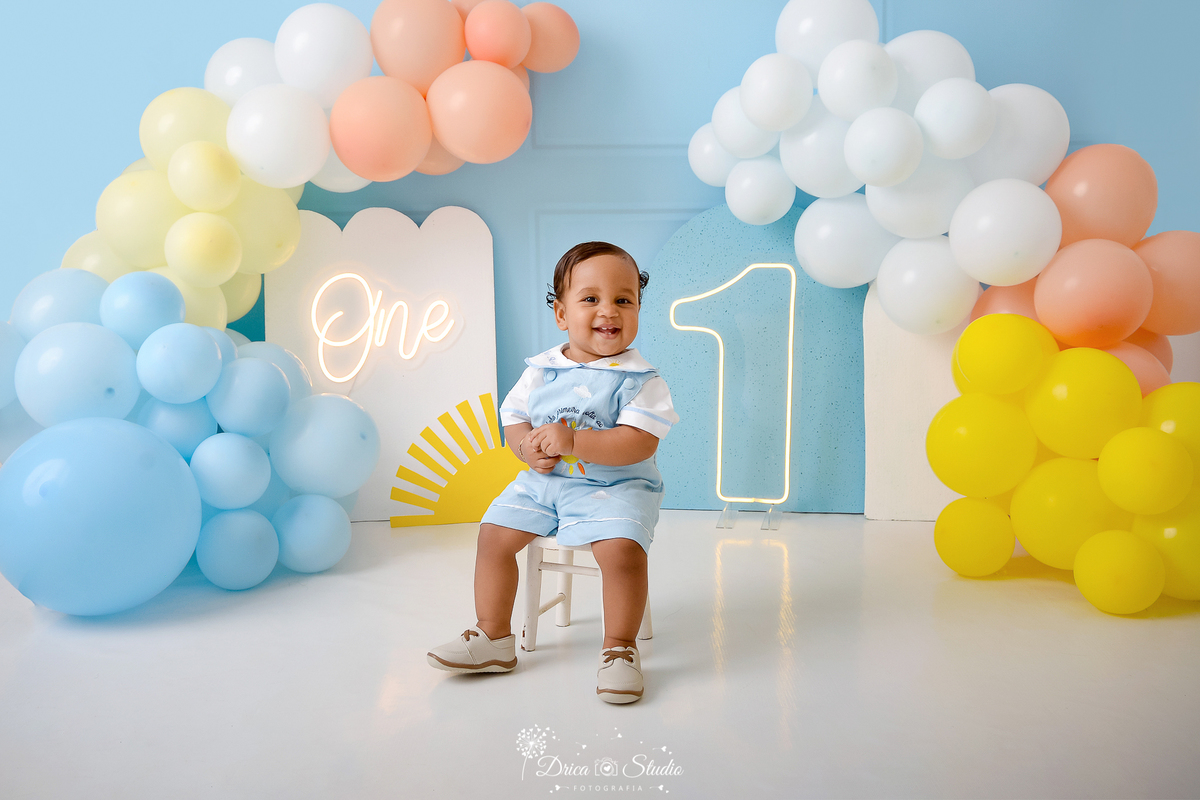 drica studio - ensaio fotografico infantil - smahs the cake - minha primeira volta ao sol - xinguara - bebê sentado em baquinho branco vestindi macaquinho azul claro e camisa branca - solzinho - hum de led - one de led - painel branco - 