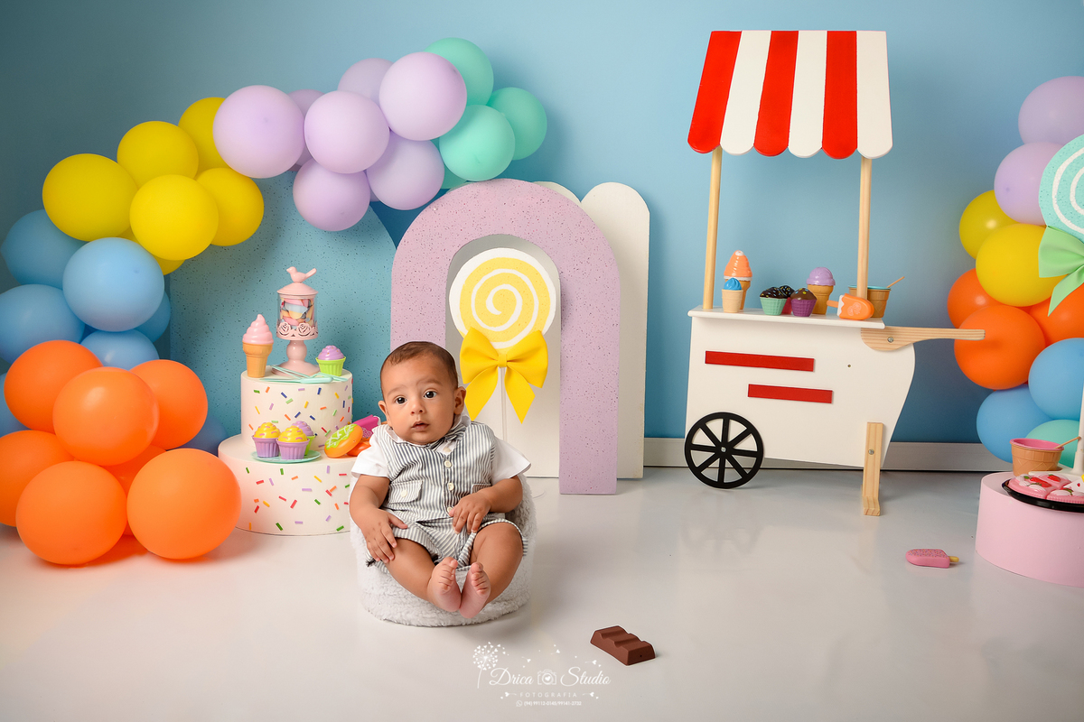drica studio - ensaio fotográfico infantil - xinguara - acompanhamento mensal  - bebê sentado em poltrona - sorvete, chocolate, picole, docinhos e torta de brinquedo - carrinho de sorvete - fundo azul claro - balões coloridos - 