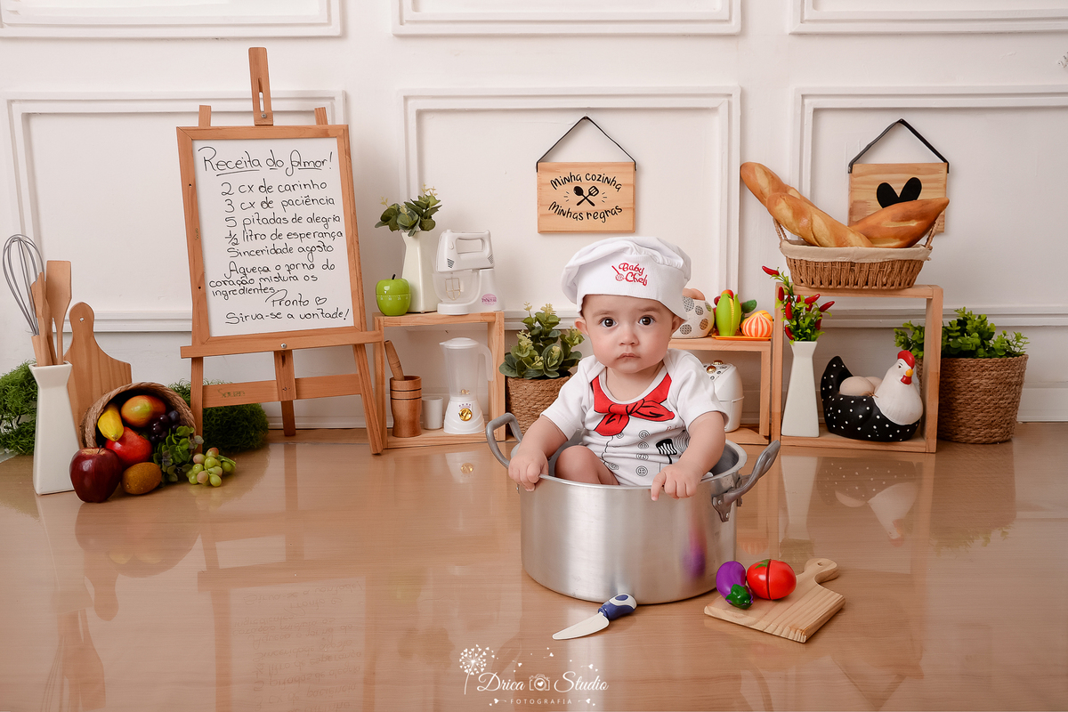 drica studio - ensaio fotográfico infantil - acompanhamento - bebê sentado dentro de panela - frutas dentro de cesto de palha - cesto com pães - tabúa de cortar legumes - utensilios de cozinha - quadrinhos decorativos - fundo branco