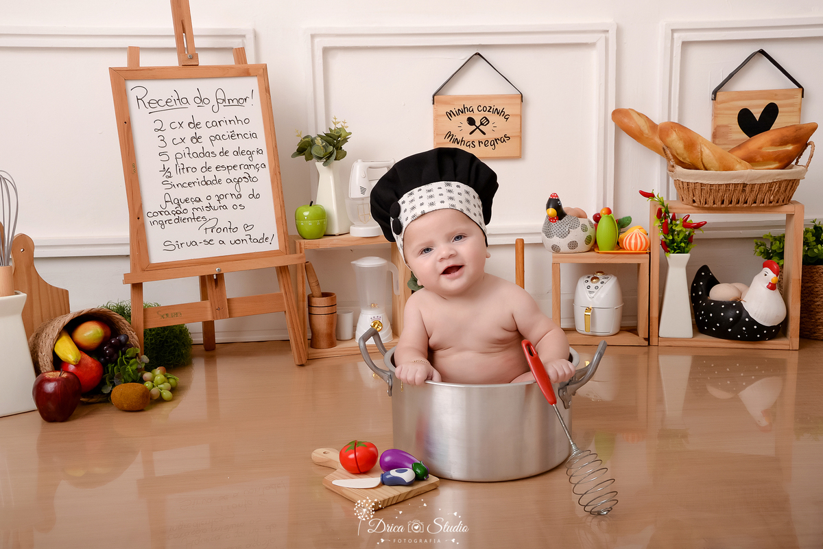 drica studio - ensaio fotográfico infantil - acompanhamento - bebê sem camisa, sentado dentro de panela com chapéu de chef de cozinha na cabeção, segurando batedor de massa - cesto de frutas - cesto de pães - panela eletrica - fundo branco - 