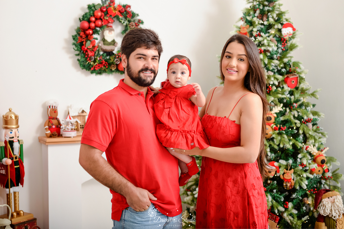 drica studio - ensaio fotografico - xinguara - fotos de natal - vestindo vermelho - camisa vermelha - árvore de natal - guirlanda - quebra nozes - laleira branca - fundo branco - casal segurando bebê no colo