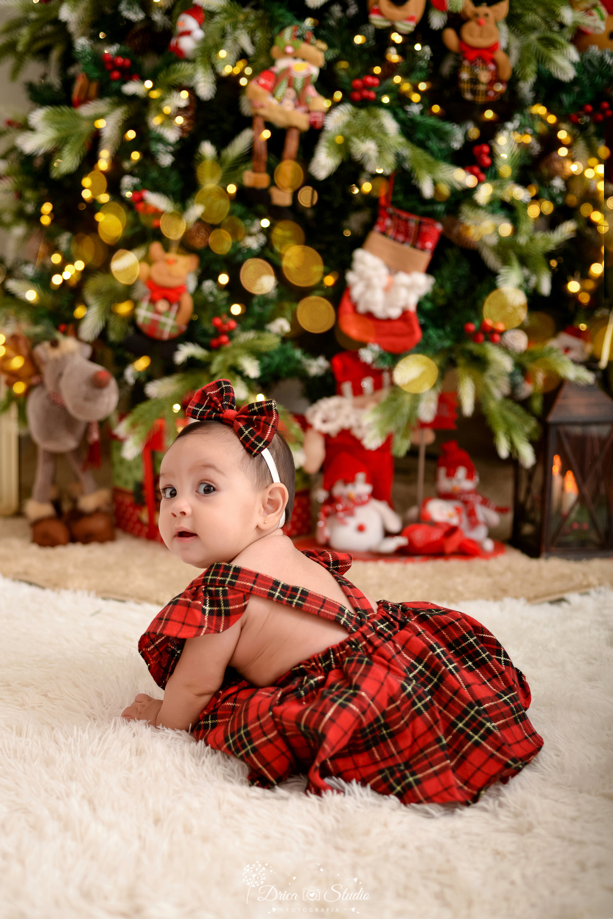 drica studio - ensaio fotografico - xinguara - fotos de natal - bebê engatinhando, vestida com jardineira xadrez vermelho - árvore de natal - boneco de neve de pelucia - rena de pelucia - lampião rustico 