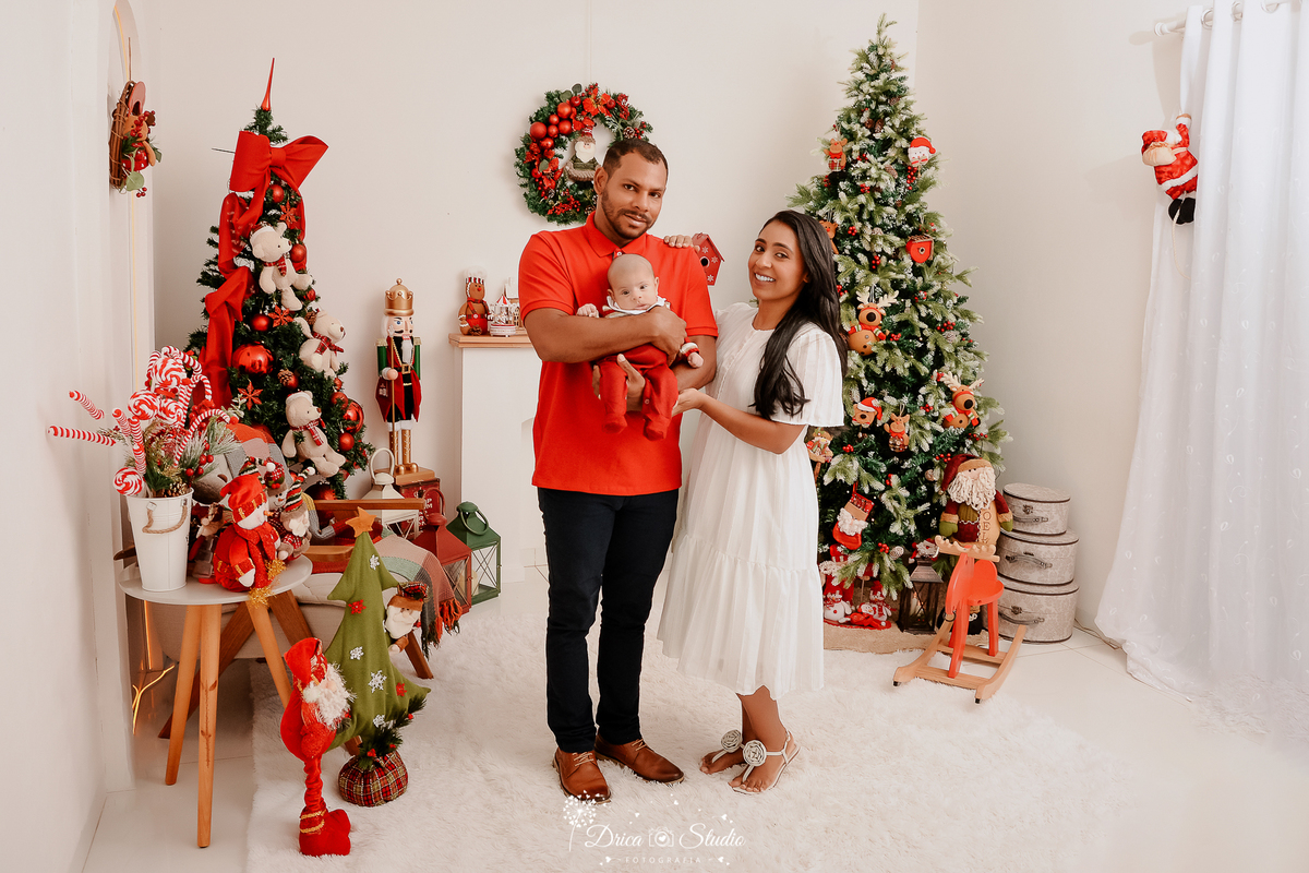 drica studio - ensaio fotografico - xinguara - fotos de natal - camisa vermelha - vestido branco - bebê usando maquinho de veludo vermelho - árvore de natal - decoração de natal - quebra nozes - rena vermelha de madeira - guirlanda - papai noel de pelúcia