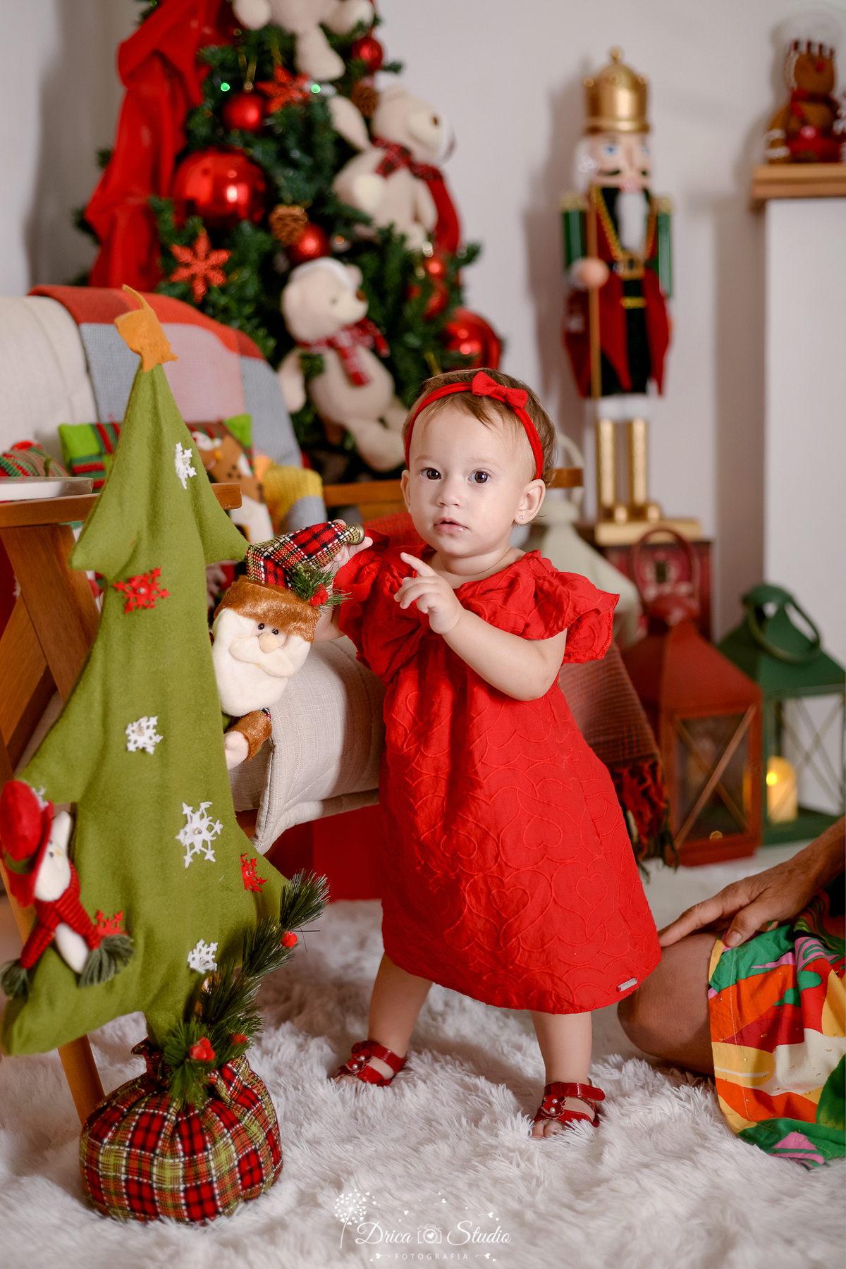 drica studio - ensaio fotografico - xinguara - fotos de natal - bebê em pé próximo a árvore de natal de feltro - lampião vermelho e lampião verde - quebra nozes