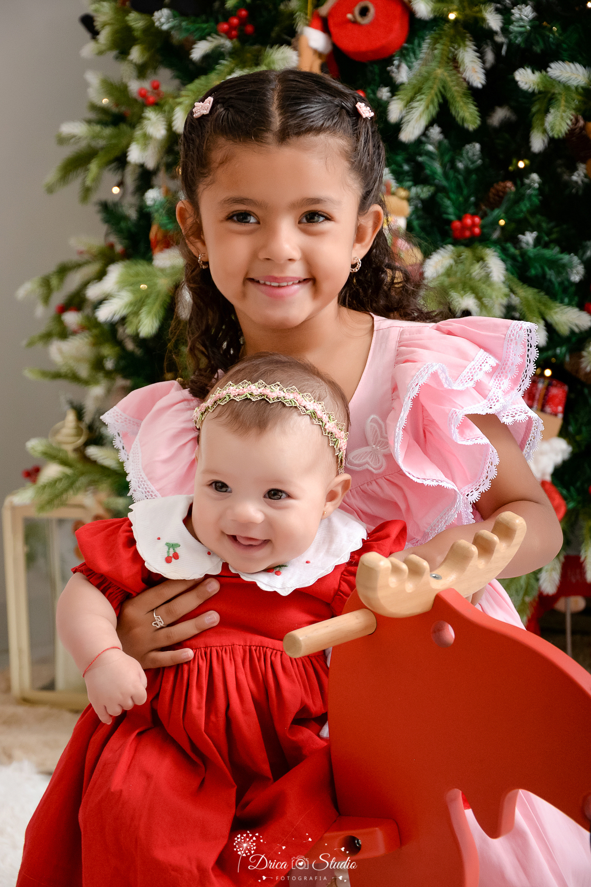 drica studio - ensaio fotografico - xinguara - fotos de natal - vestido rosa - vestido vermelho com babado branco - riara de pérolas - árvore de natal - rena vermelha de madeira