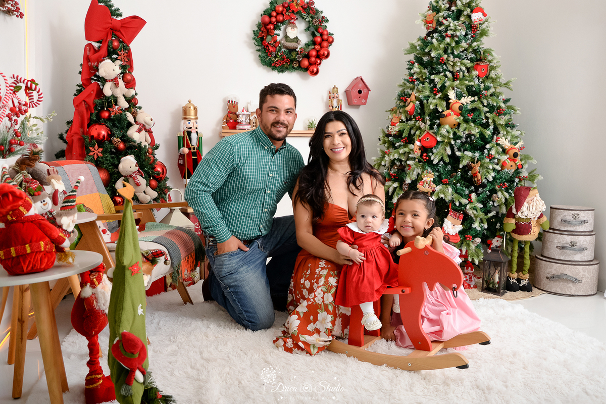 drica studio - ensaio fotografico - xinguara - fotos de natal - homem veste camisa xadres verde, mulher usa vestido de alcinhas logo terracota, bebê veste vestindo vermelho e menina vestido rosa - árvore de natal - guirlanda - papai noel - fundo branco