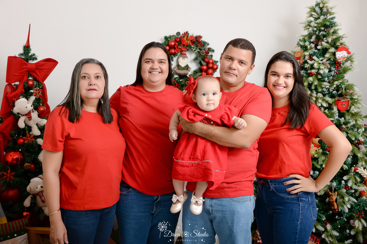 drica studio - ensaio fotografico - xinguara - fotos de natal - camisa vermelha e calça jeans - árvore de natal - guirlanda - usinhos natalino - fundo branco - bebê usando vestindo vermelho com laço lateral na cabeça
