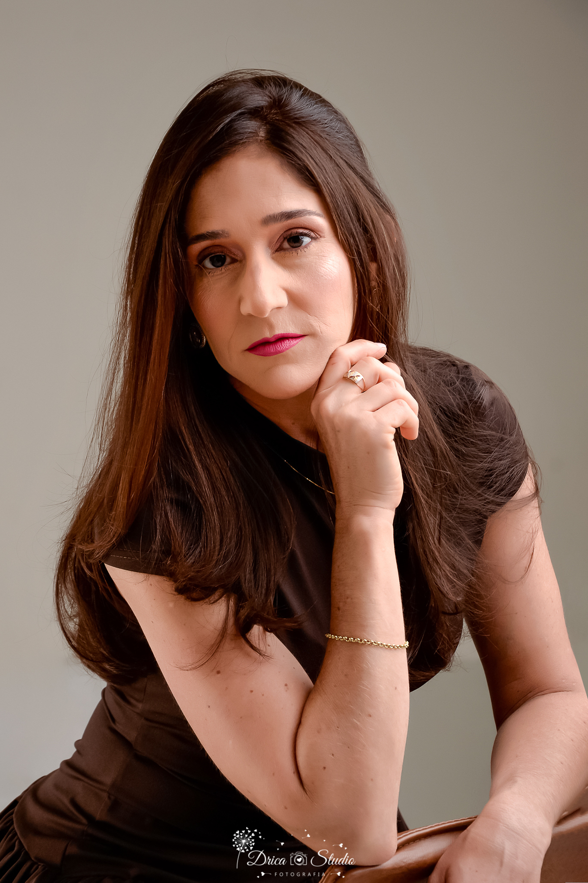 drica studio fotográfico - ensaio aniversário 40 anos - xinguara - pará - mulher sentanda em cadeira apoiando braço no encosto - cadeira de couro - fundo branco