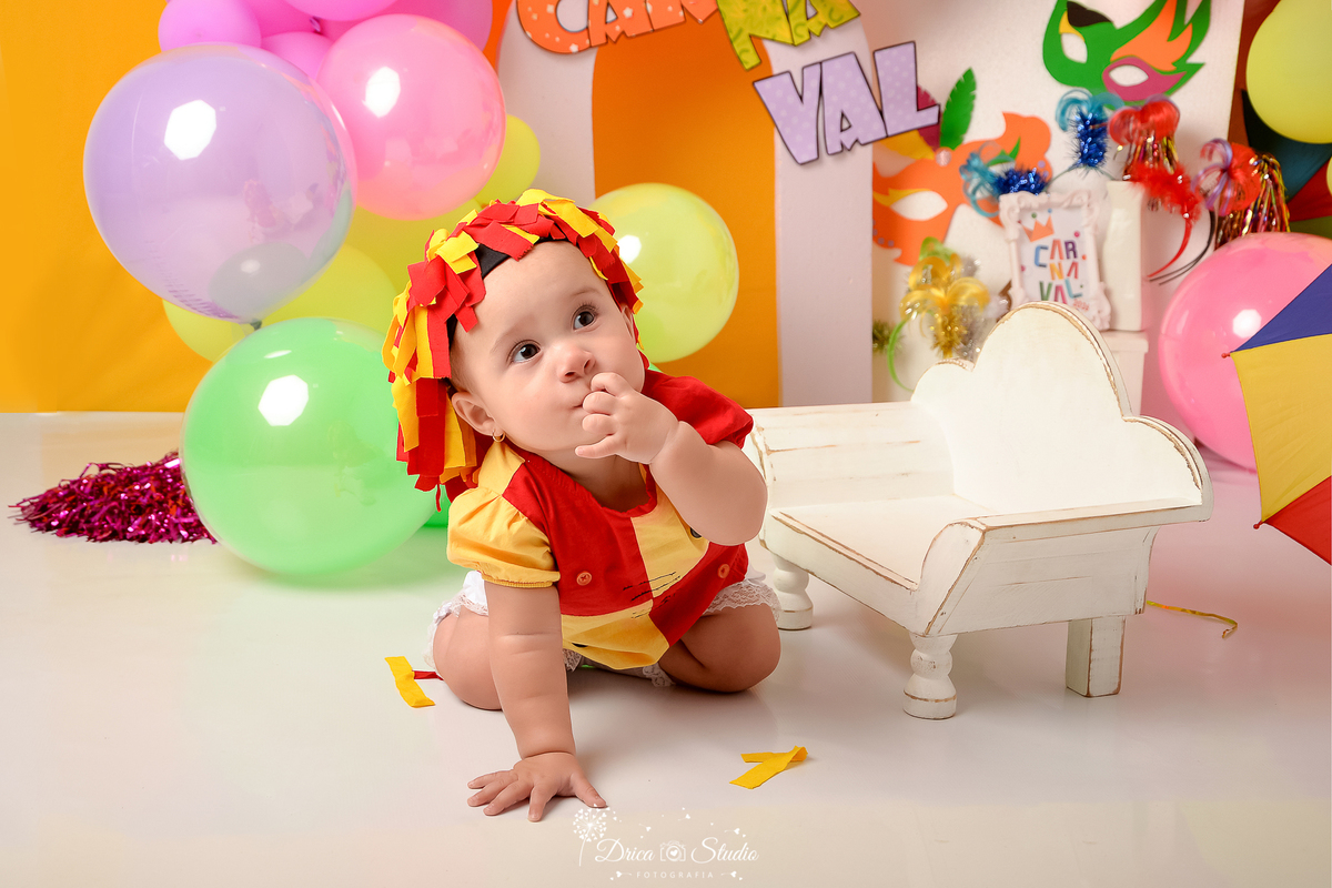 drica studio - ensaio fotográfico infantil - carnaval- xinguara - pará - banquinho branco - bebê usando roupinha de emília - máscara de carnaval - painel branco e lilas - balões coloridos - fundo amarelo