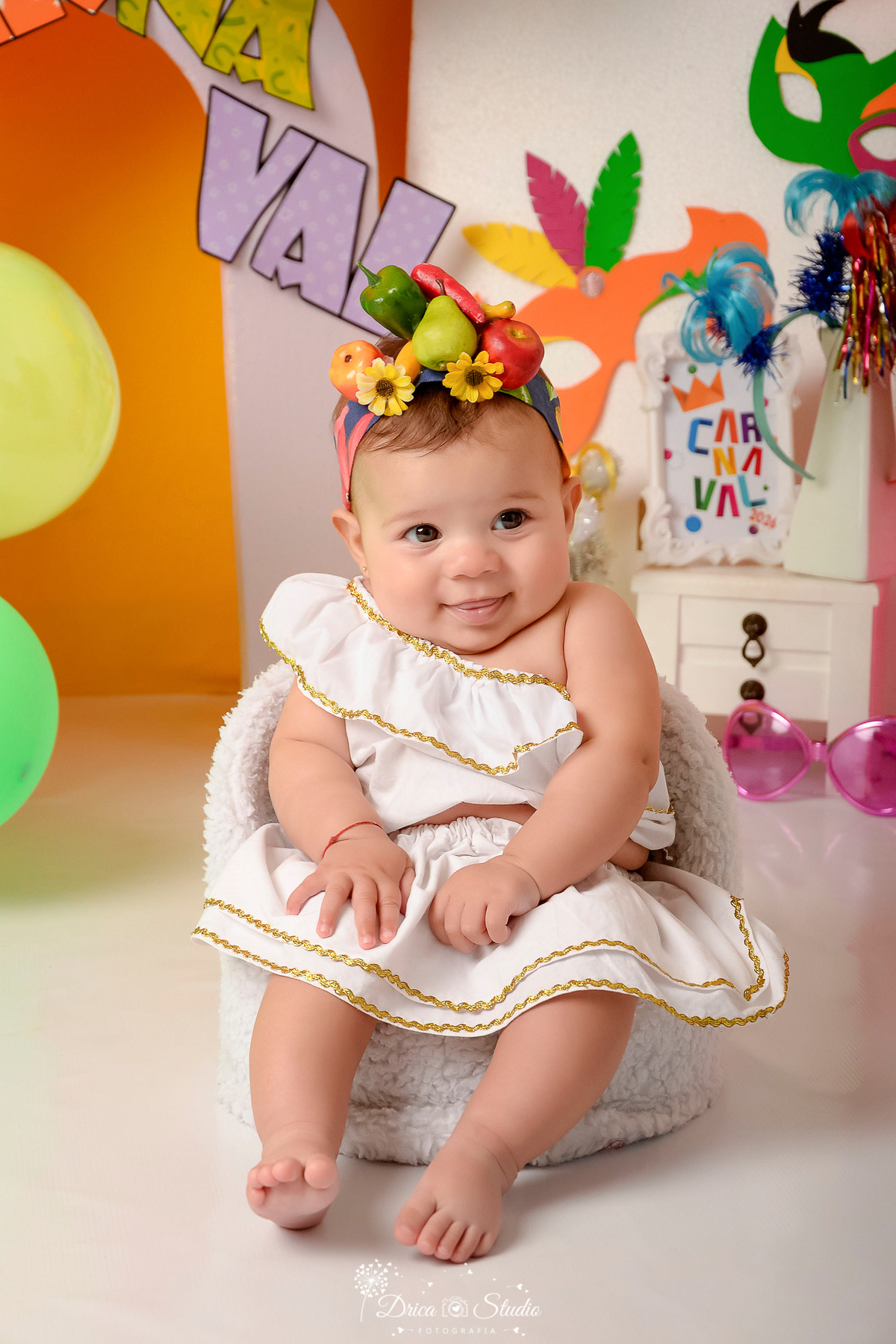 drica studio - ensaio fotográfico infantil - carnaval- xinguara - pará - bebê sentada em poltrona branca, vestida de carmem miranda com frutinhas na cabeça - penteadeira branca - painel lilas - fundo amarelo - óculos rosa