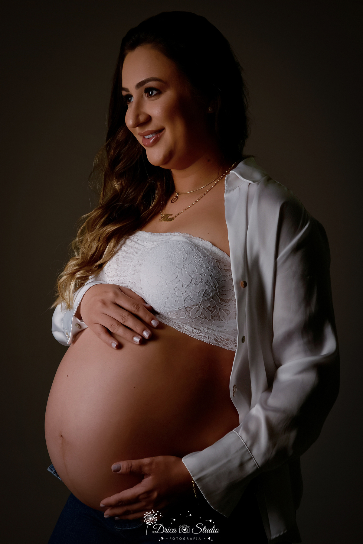 drica studio - ensaio fotografico gestação - xinguara - pará - gestante posa para foto usando calça jean, top e camisa branca aberta deixando a barriga a amostra. fundo neutro