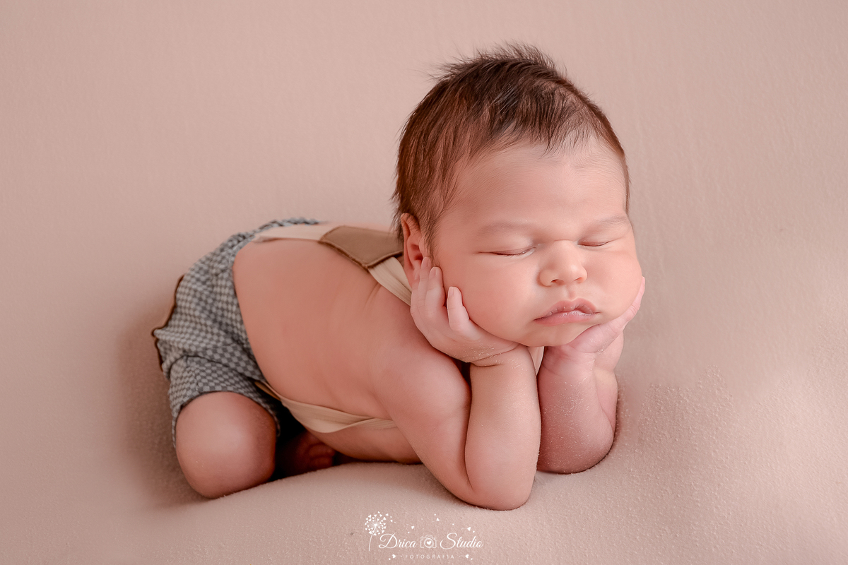 drica studio-ensaio fotografico recém-nascido- newborn-xinguara - pará - bebê recém-nascido apoiando o rostinho nas mãos - bebê veste short com suspensório sem camisa - fundo neutro