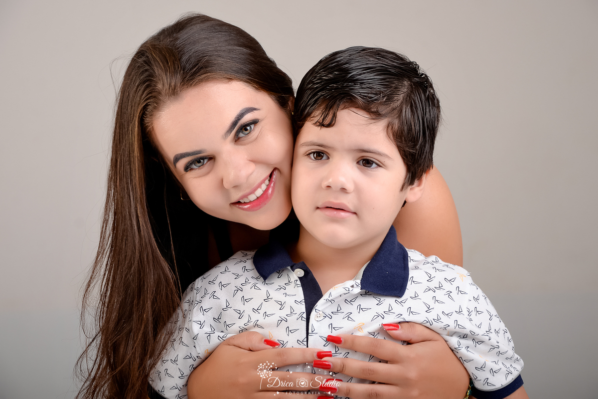 drica studio - ensaio fotografico infantil - 5 anos - xinguara - pará - mãe e filhos posam para foto, ela abraça carinhosamente o filho abraçando-o por trás - fundo neutro