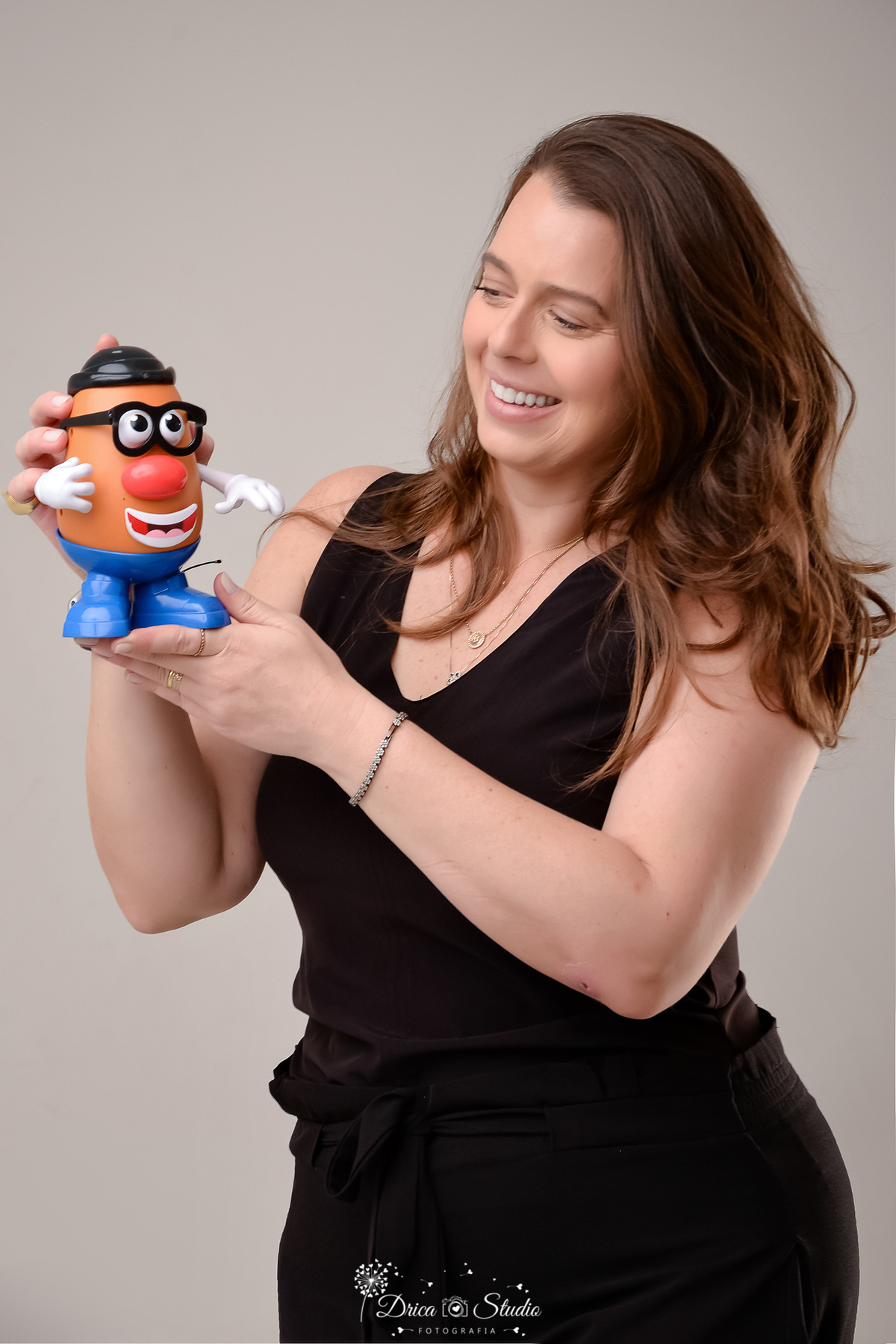 drica studio - ensaio fotografico profissional - psicologia infantil - xinguara - pará- Psicóloga segurando brinquedo terapêutico em ensaio profissional descontraído - ela veste blusa preta - fundo neutro